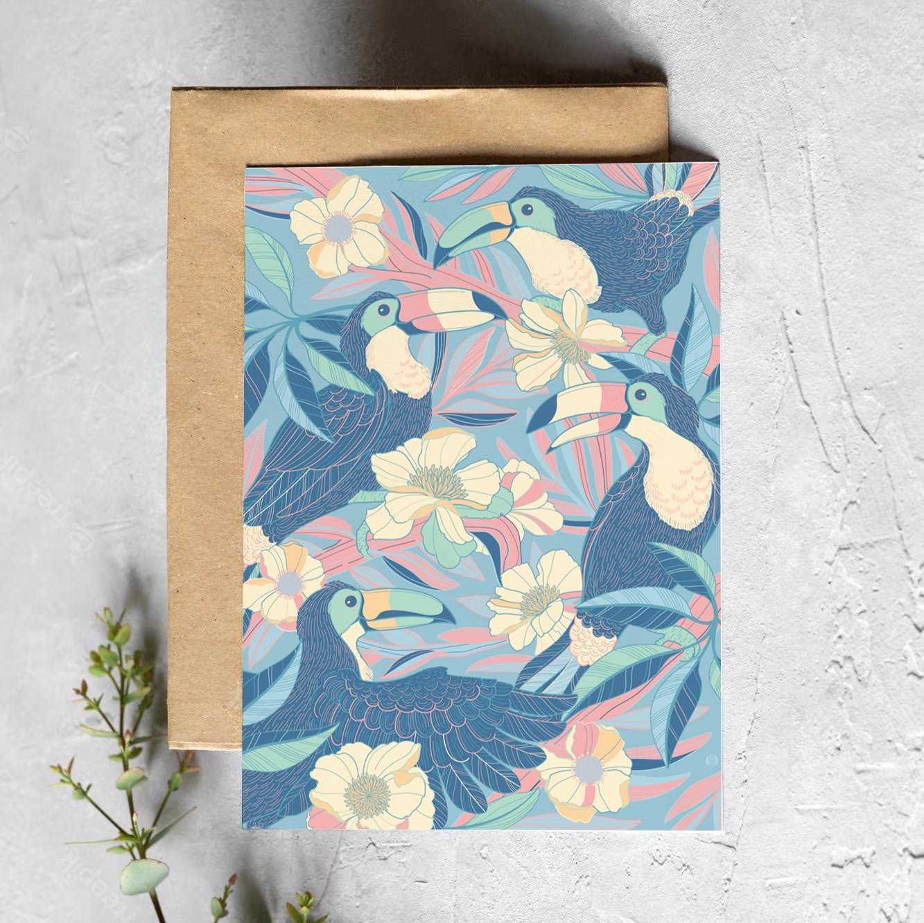 Colorful toucans surrounded by floral designs on a card with a brown envelope, showcasing tropical art.