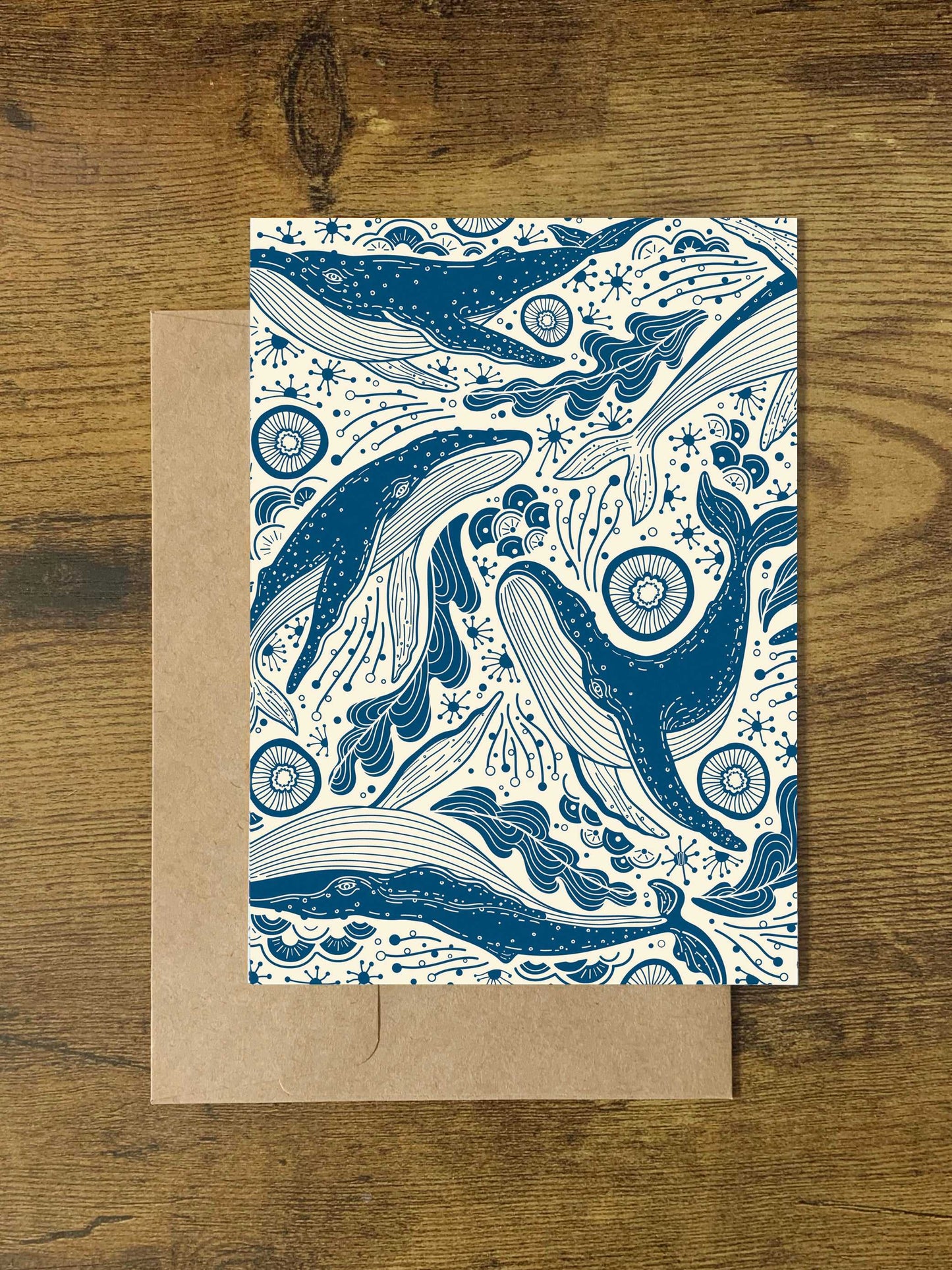 Illustrated Humpback Whales and ocean waves design on a card, set on a wooden background.