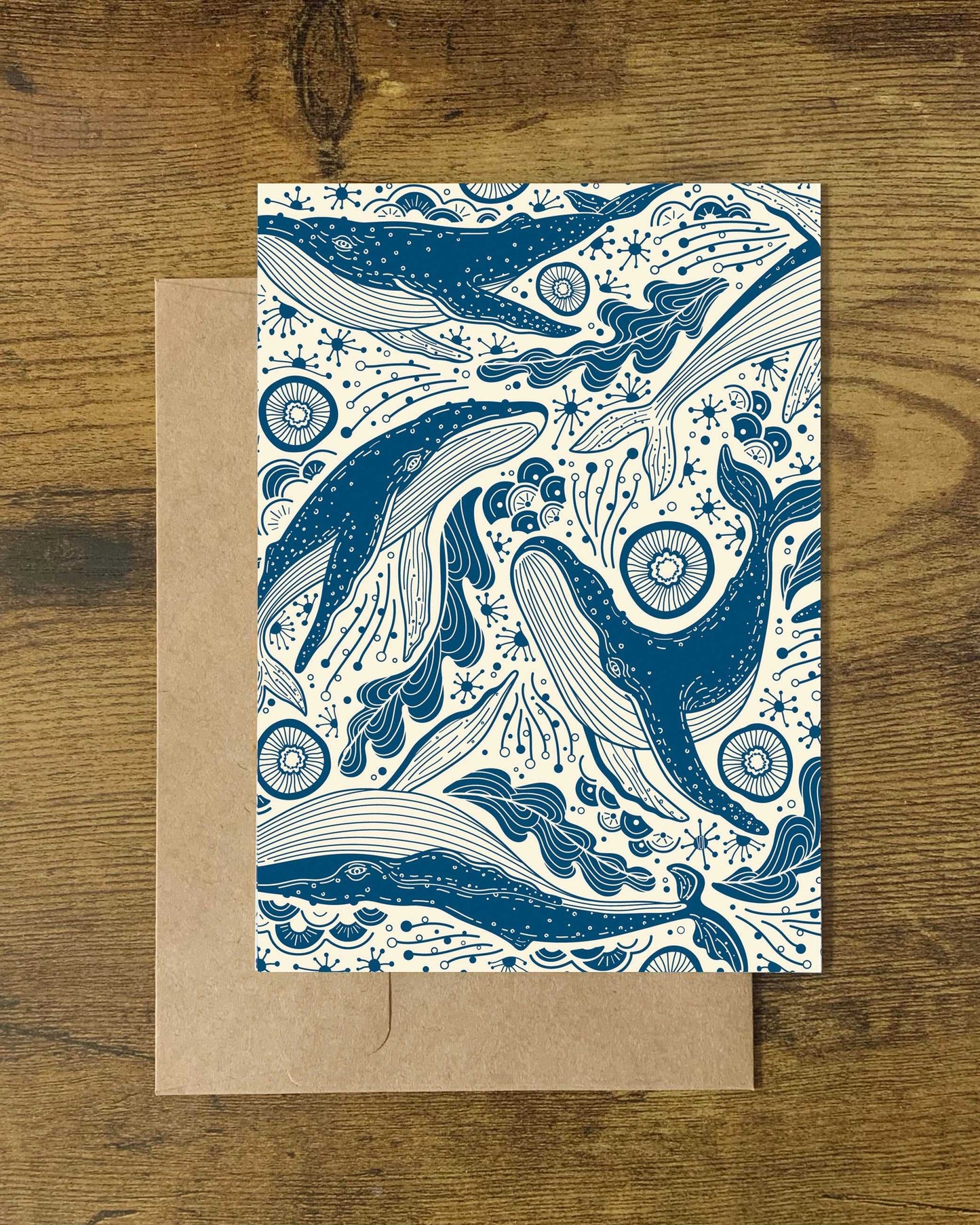 Whale and ocean inspired art card on a wooden surface, featuring blue and white whale illustrations.
