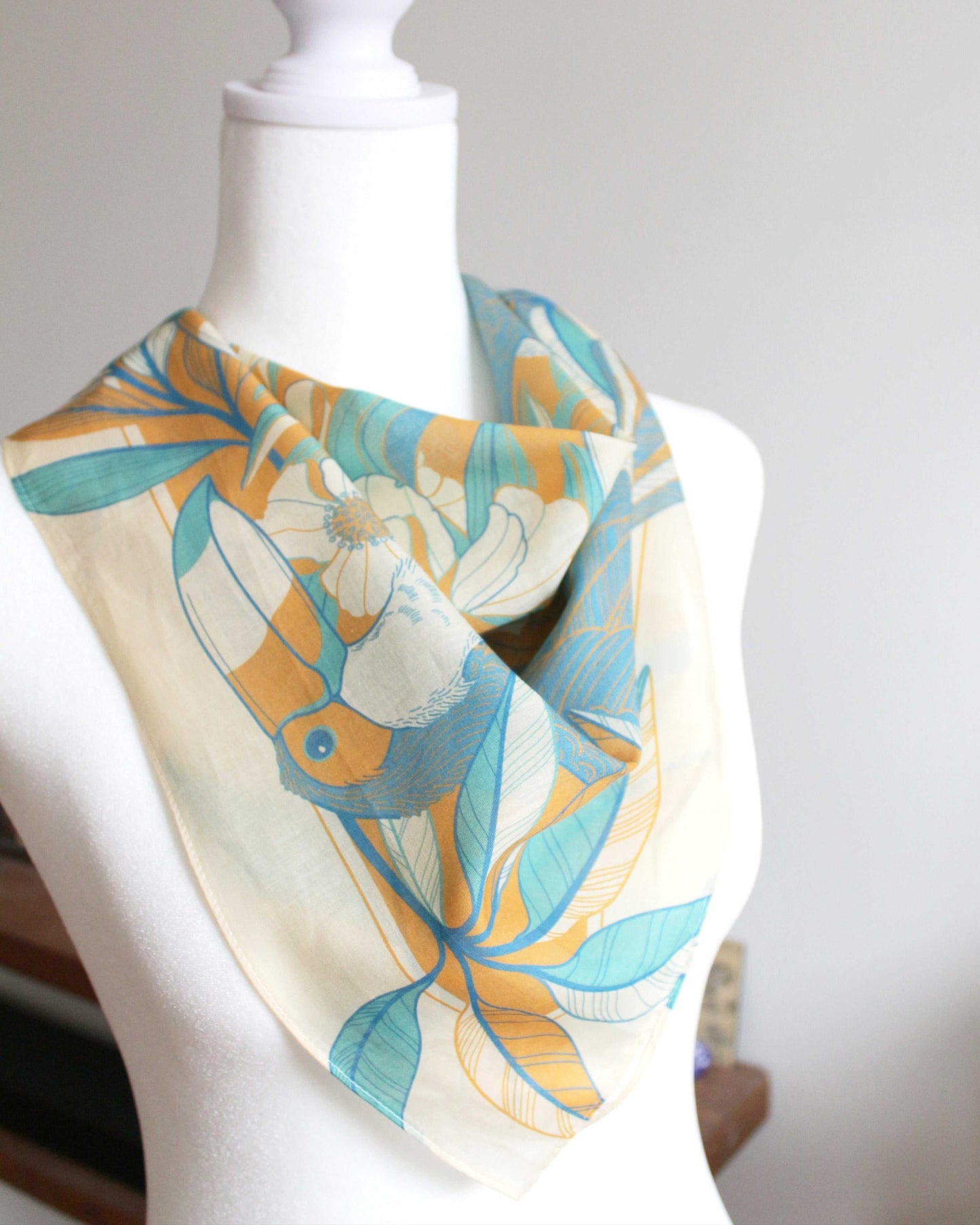 Toucan in Floral Jungle Bandana Scarf in yellow, showcasing tropical design on a mannequin, perfect for summer styling.