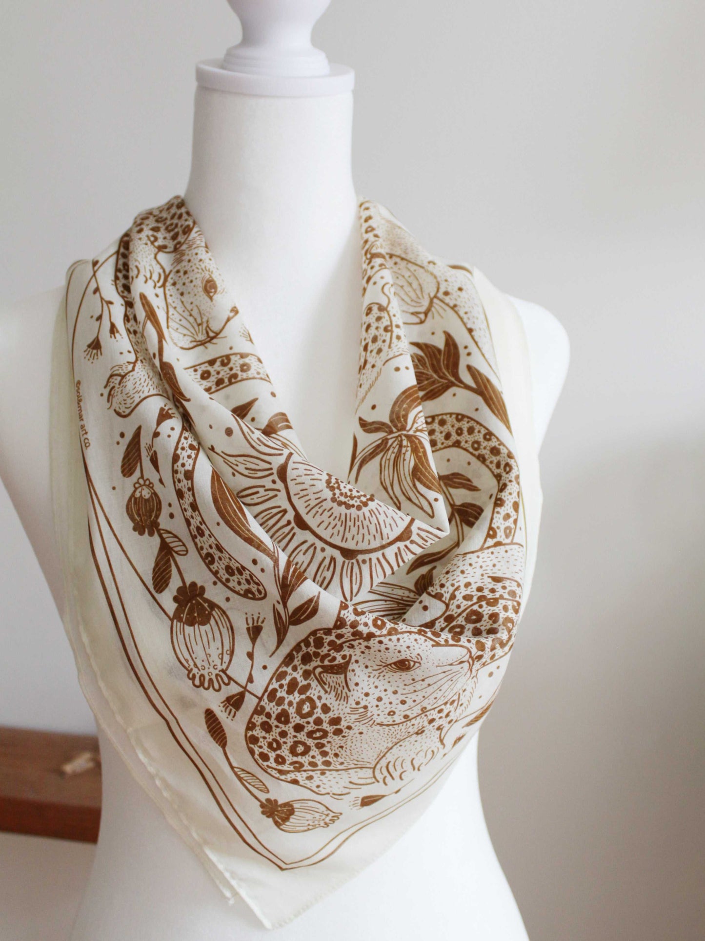 Leopard and the Sun off-white bandana scarf featuring line art, displayed on a mannequin.