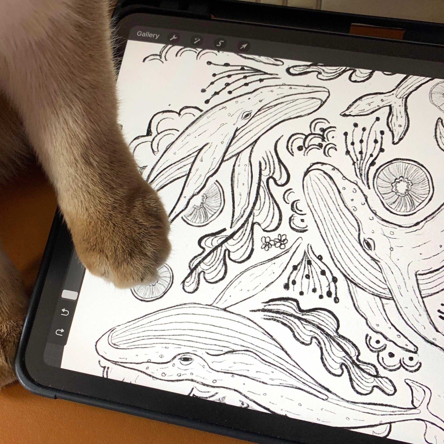 Close-up of a digital drawing of humpback whales, featuring detailed line art, with a cat's paw in the foreground.