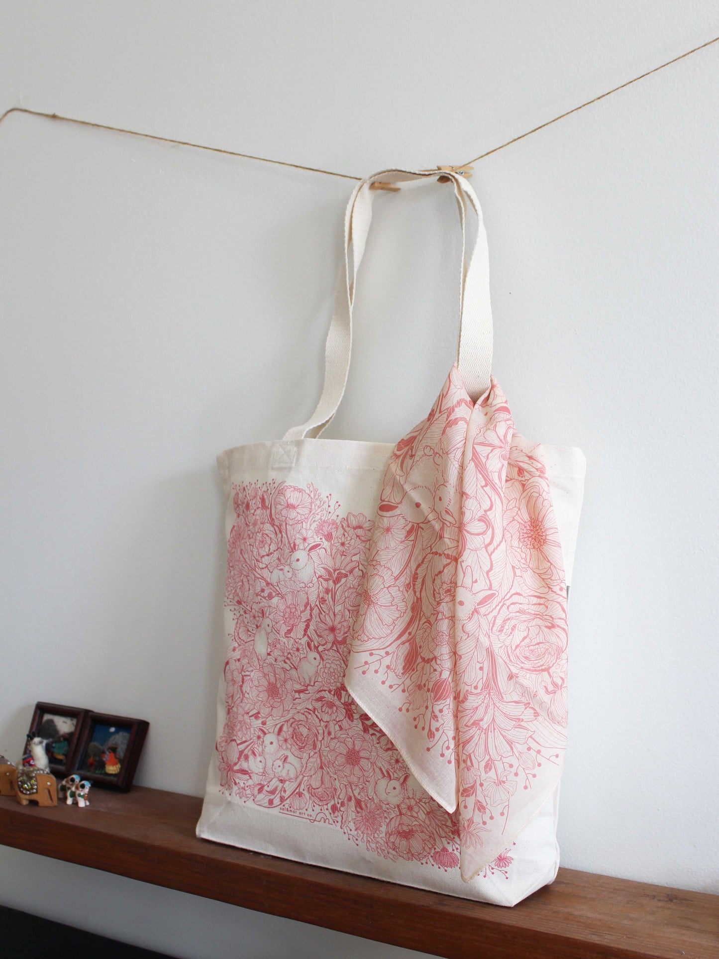 Pastel pink floral bandana scarf draped on a tote bag, showcasing a stylish accessory for any occasion.