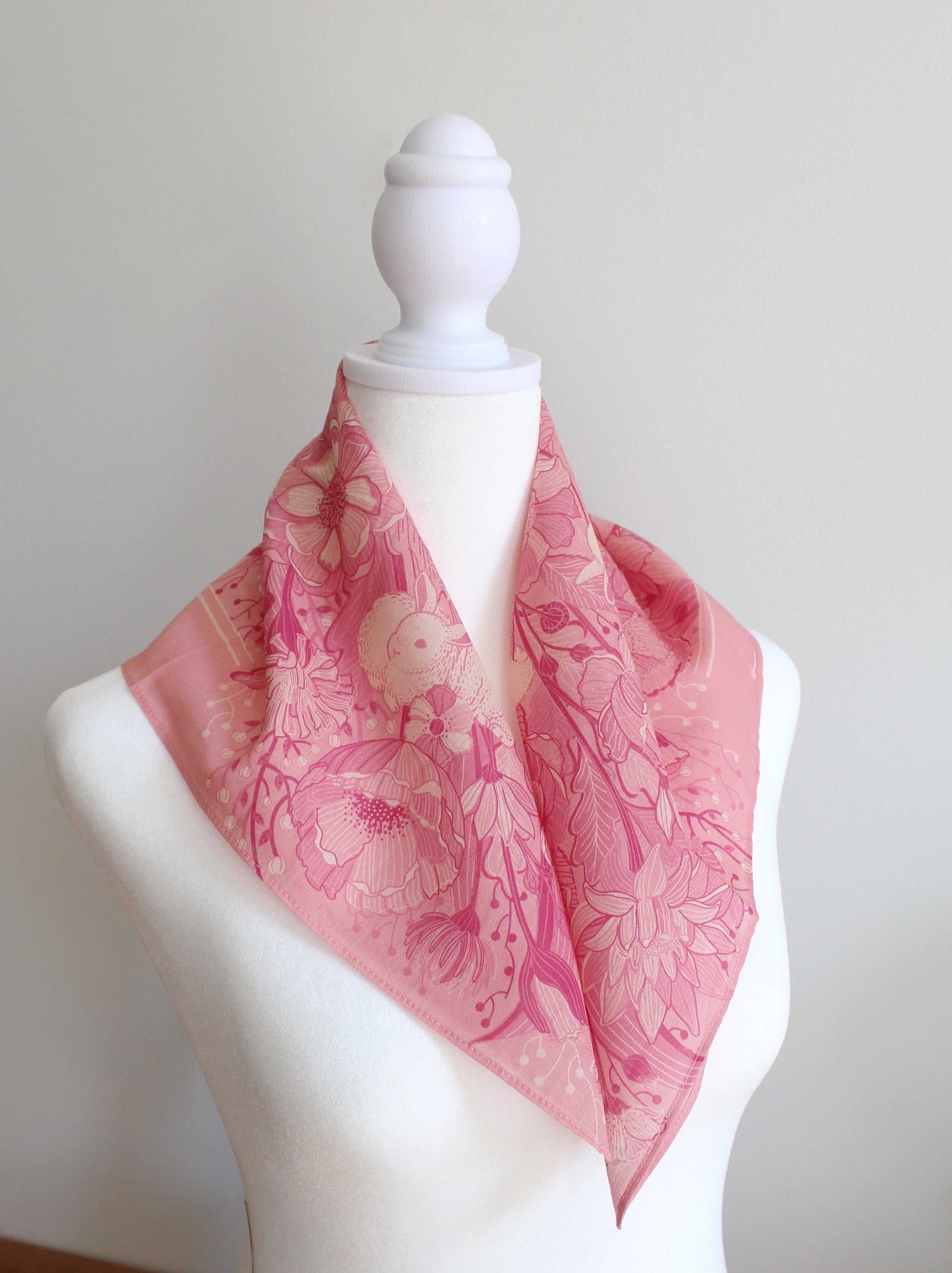 Bunny in Floral Breeze Bandana Scarf in pink, featuring floral and rabbit artwork, displayed on a dress form.