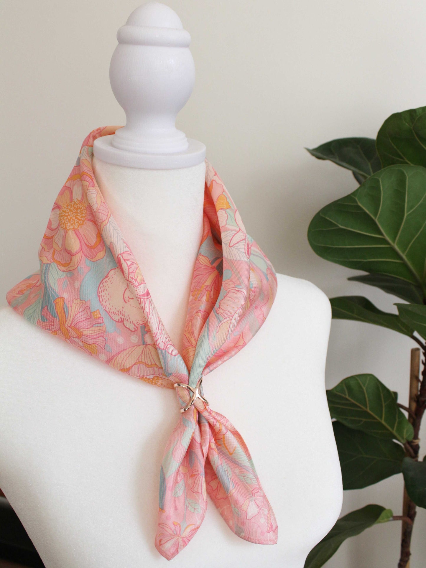 Bunny in the Floral Breeze Silk Twill Scarf tied around a mannequin neck, featuring pink floral design.