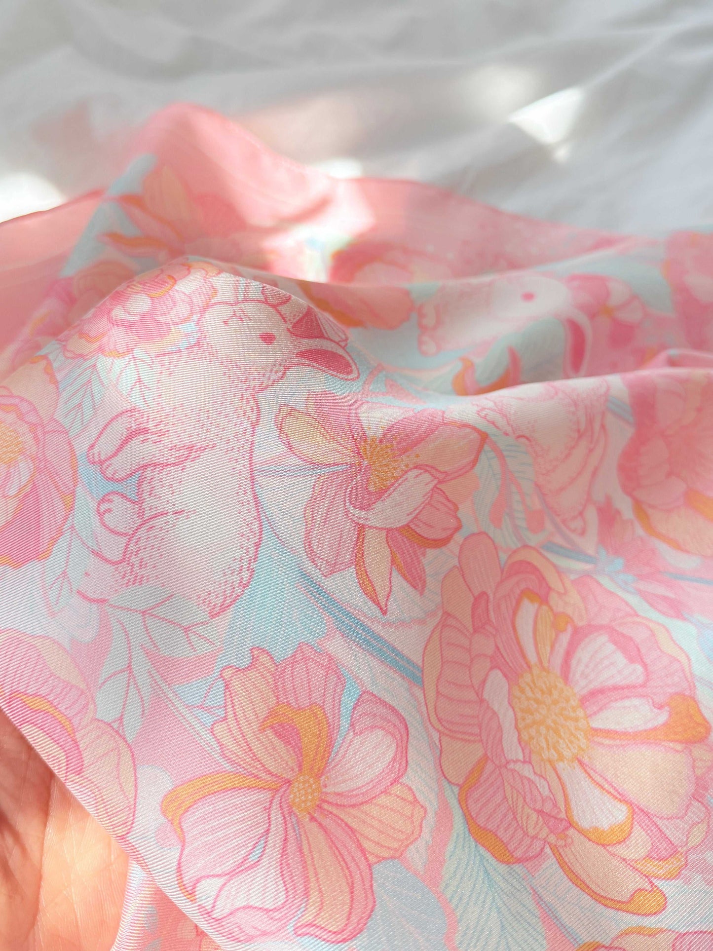 Bunny in Floral Breeze Silk Twill Scarf featuring illustrated bunnies and vibrant flowers on soft pink fabric.