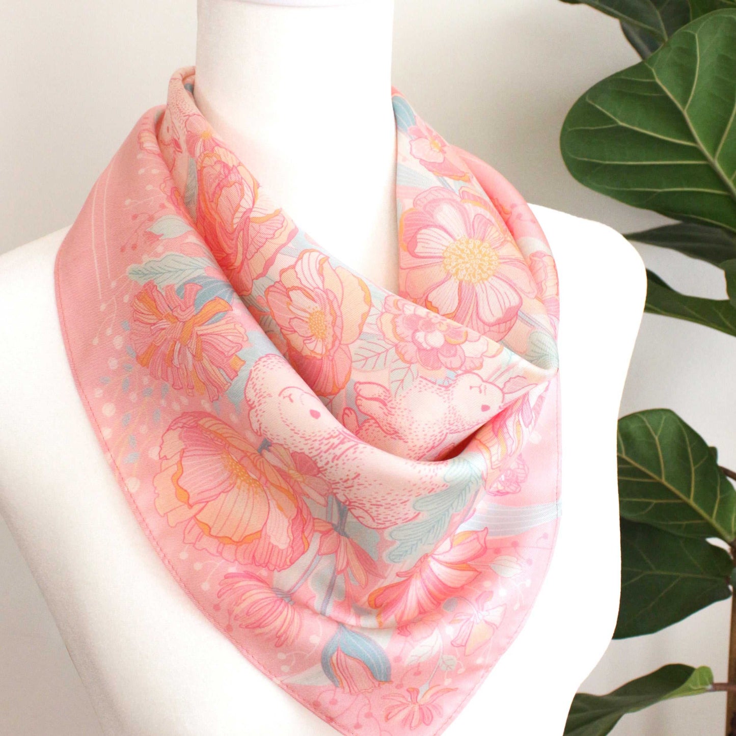 Pink silk twill scarf featuring illustrated bunnies and floral designs, perfect for accessories and decor.