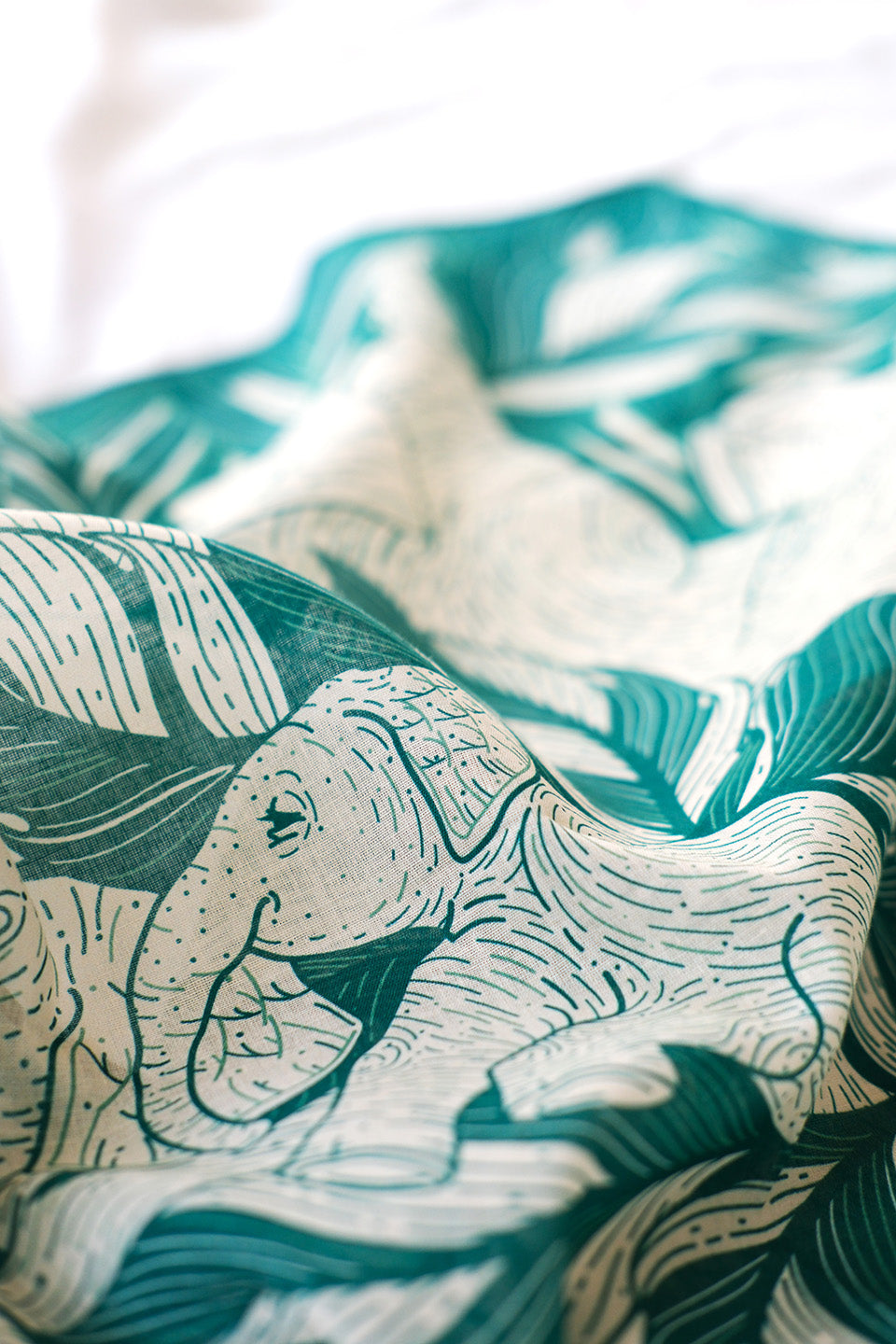 Detailed illustration of elephants in a jungle on a green bandana scarf, showcasing soft cotton fabric.