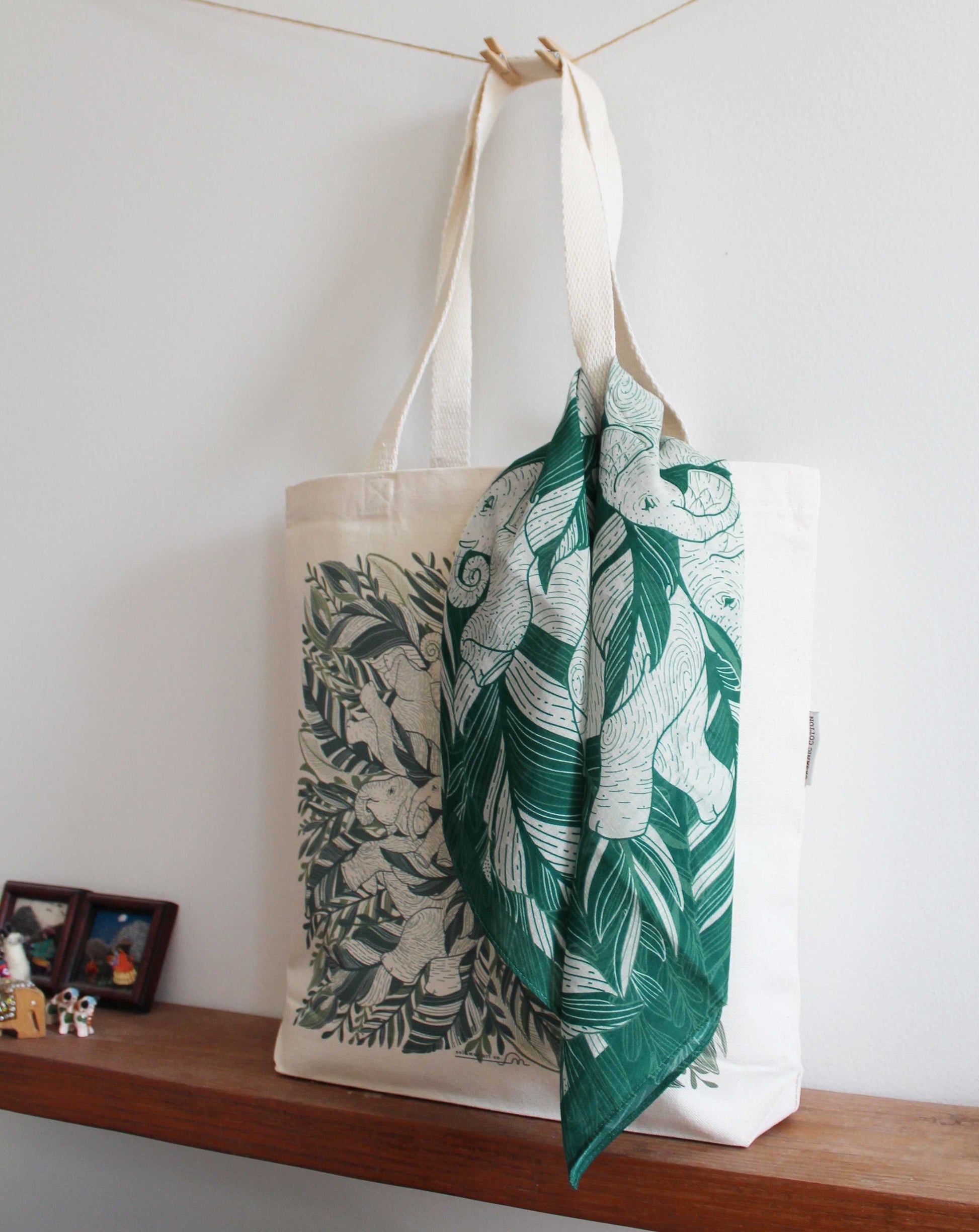 Elephant 'Siesta' bandana scarf in green tied to a tote bag with jungle artwork.