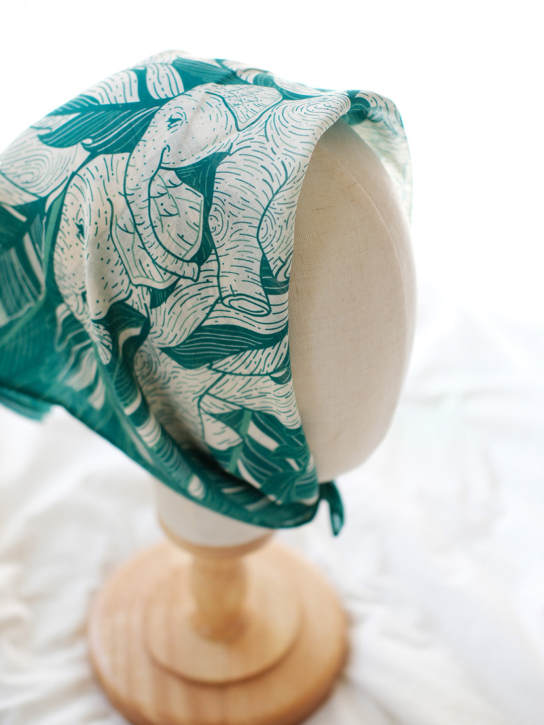 Green Elephant "Siesta" bandana scarf on a display mannequin, showcasing detailed elephant artwork.
