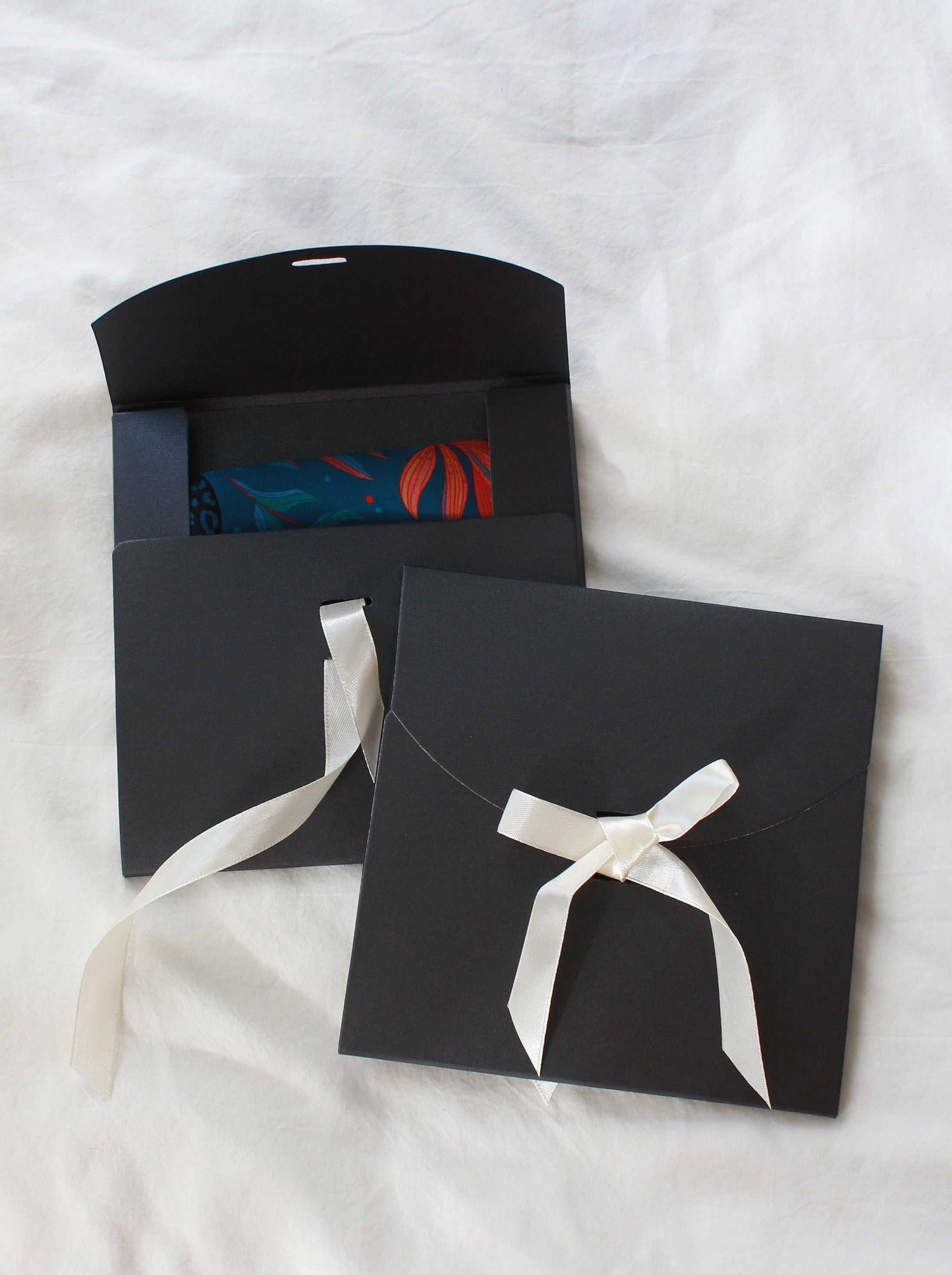 Elegant black gift envelopes with white ribbons, ideal for presenting scarves or accessories.