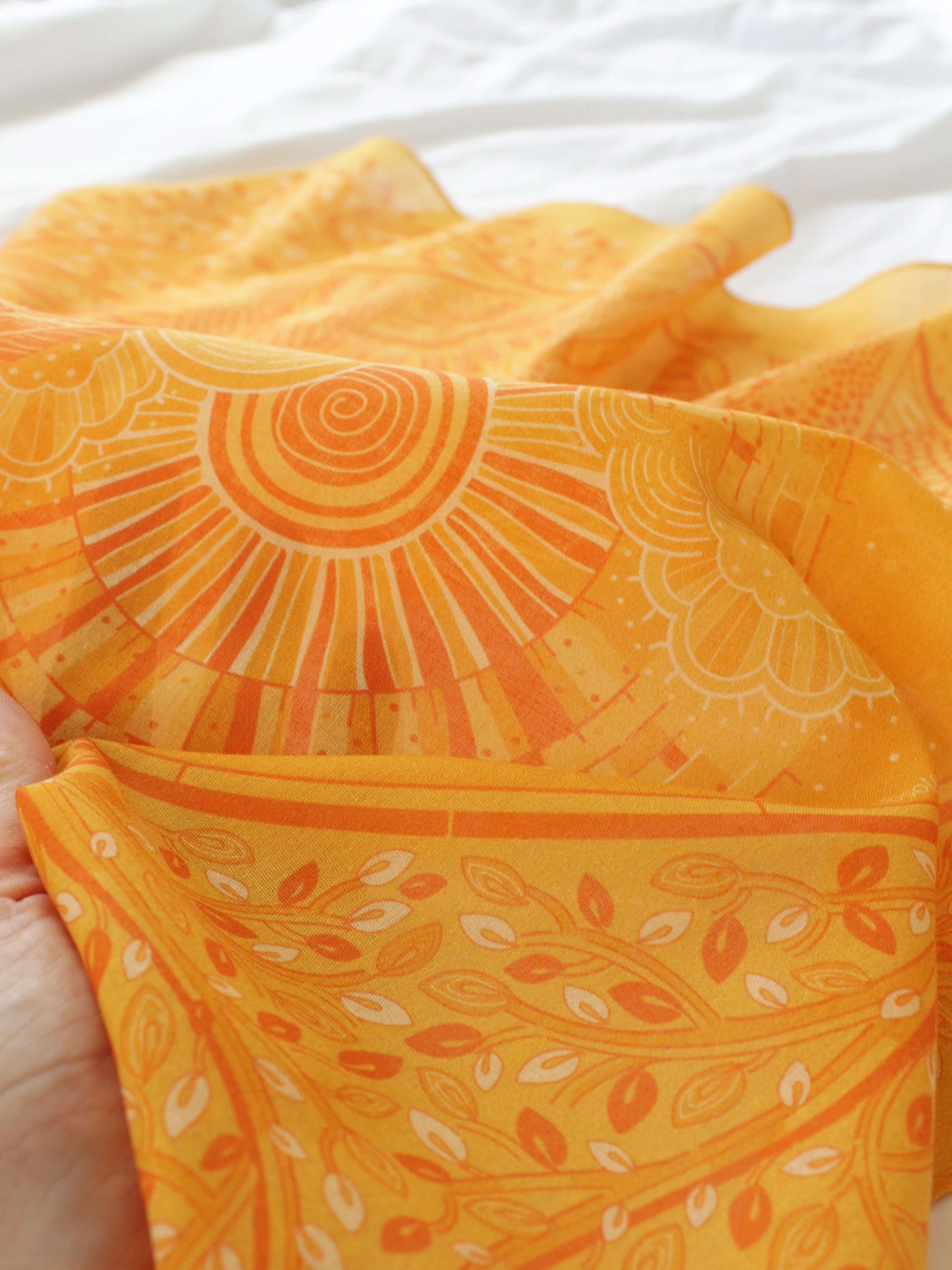 Close-up of a soft golden yellow bandana featuring intricate designs, perfect for accessorizing hair or bags.