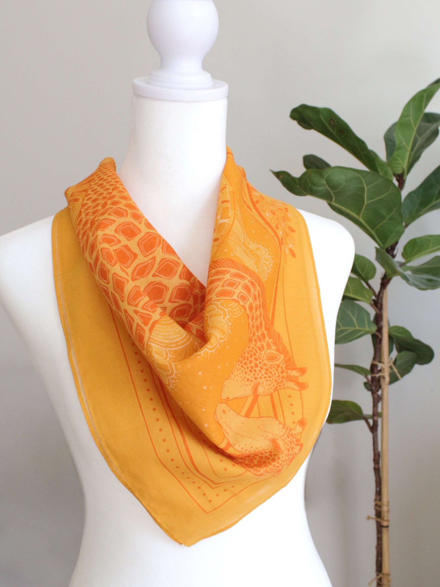 Golden yellow bandana scarf featuring a giraffe design, perfect for summer accessories and home decor.