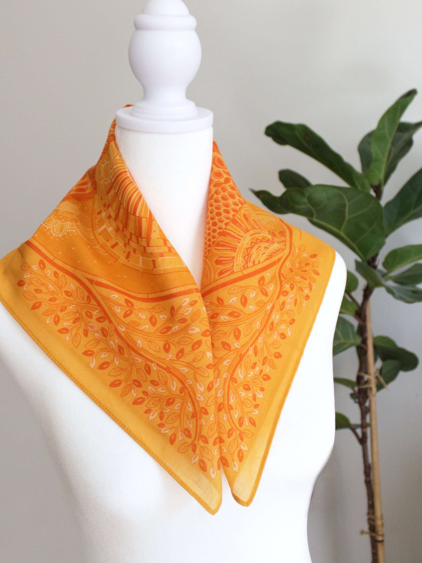 Golden yellow bandana scarf with intricate patterns displayed on a mannequin, perfect for summer styling.
