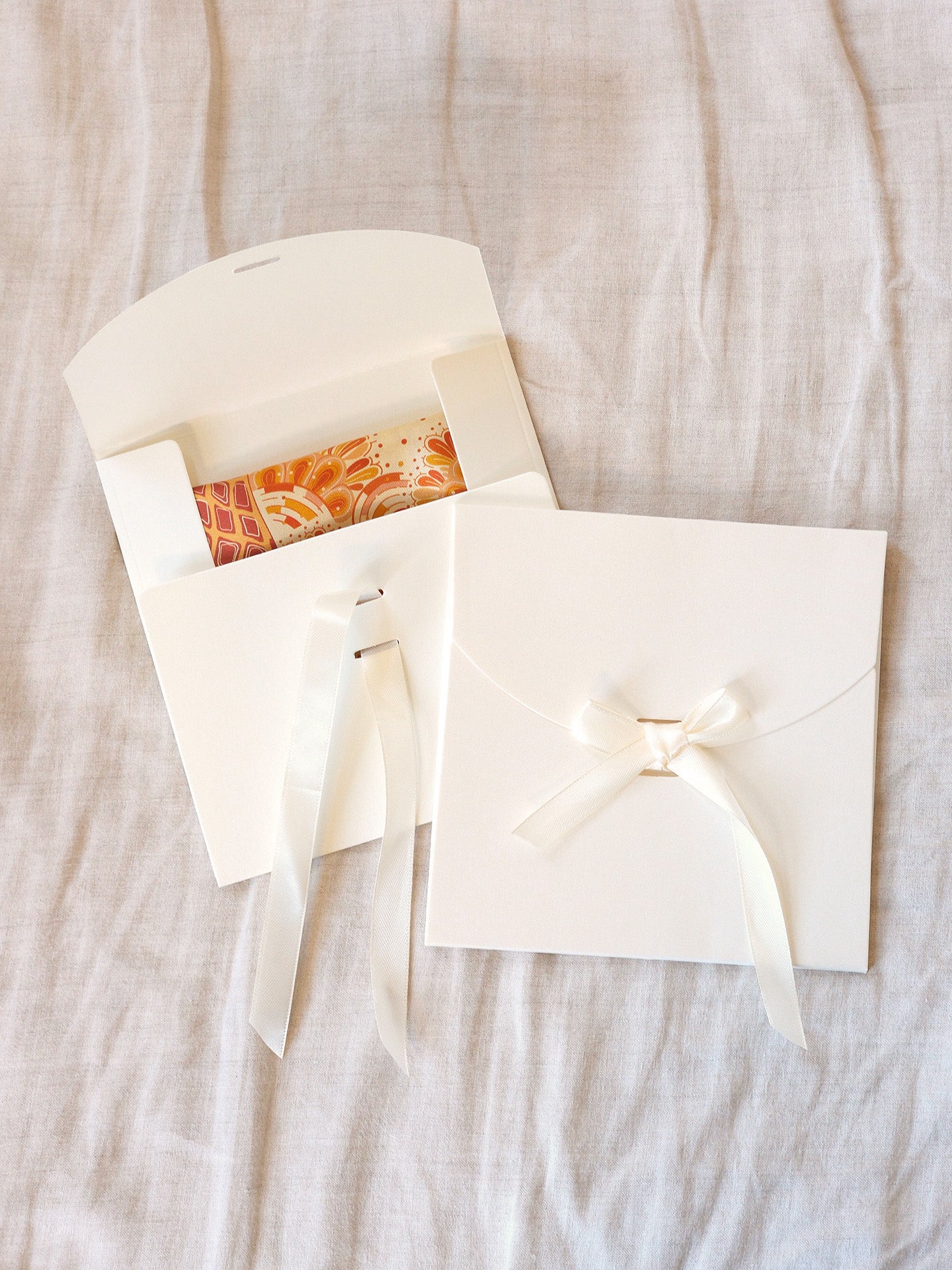 White envelope with a bow on a textured beige surface