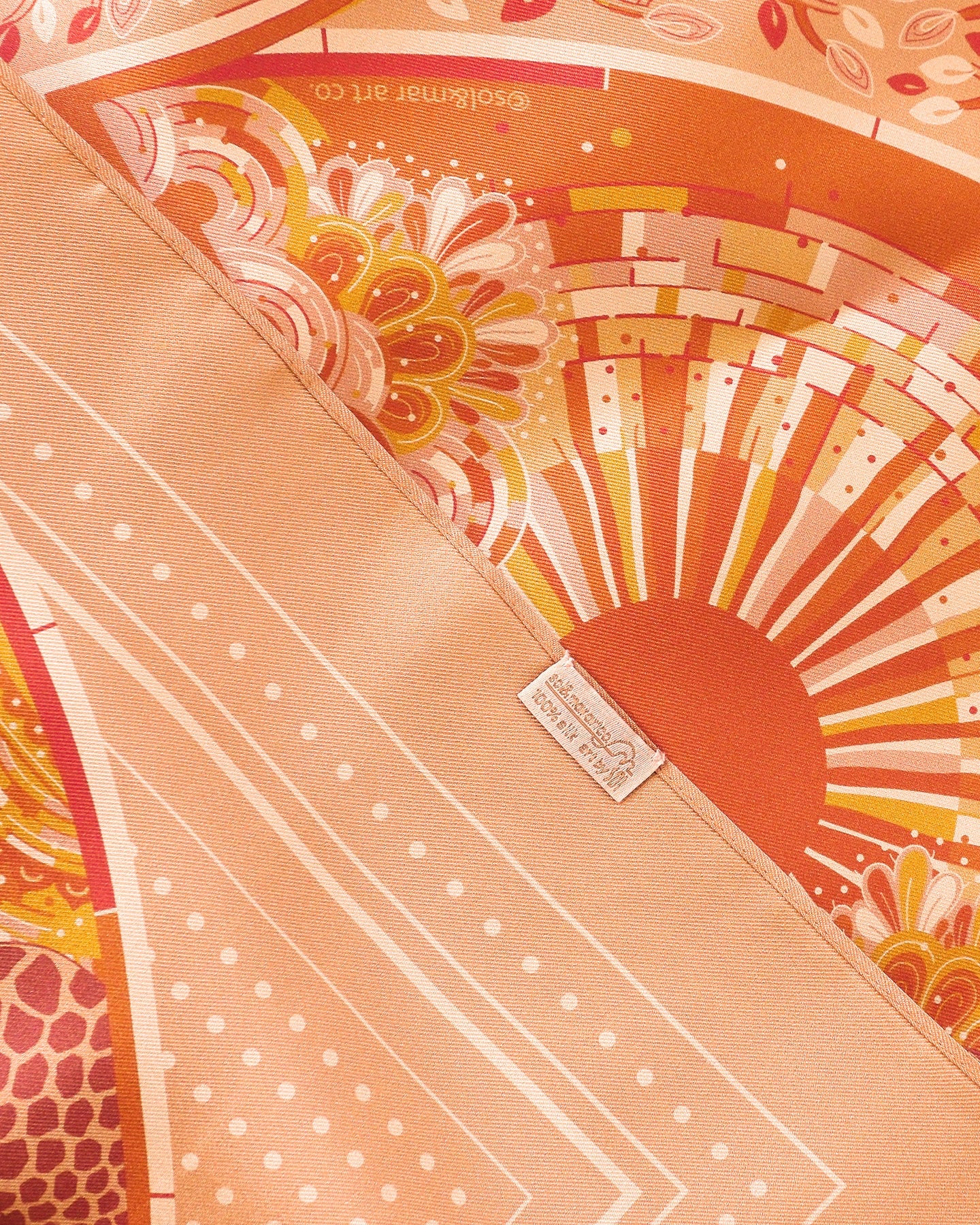 Decorative product with intricate patterns and a brand logo on an orange background