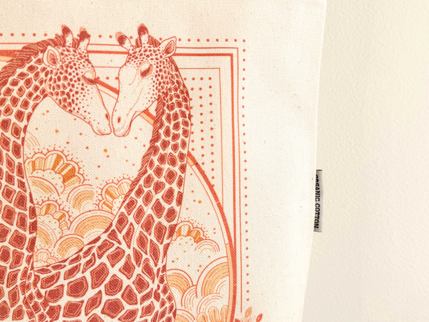 Giraffe art illustration on organic cotton canvas tote bag, featuring two giraffes in warm colors.