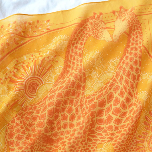 Giraffe family illustration on golden yellow bandana scarf, perfect accessory for summer styling and decor.