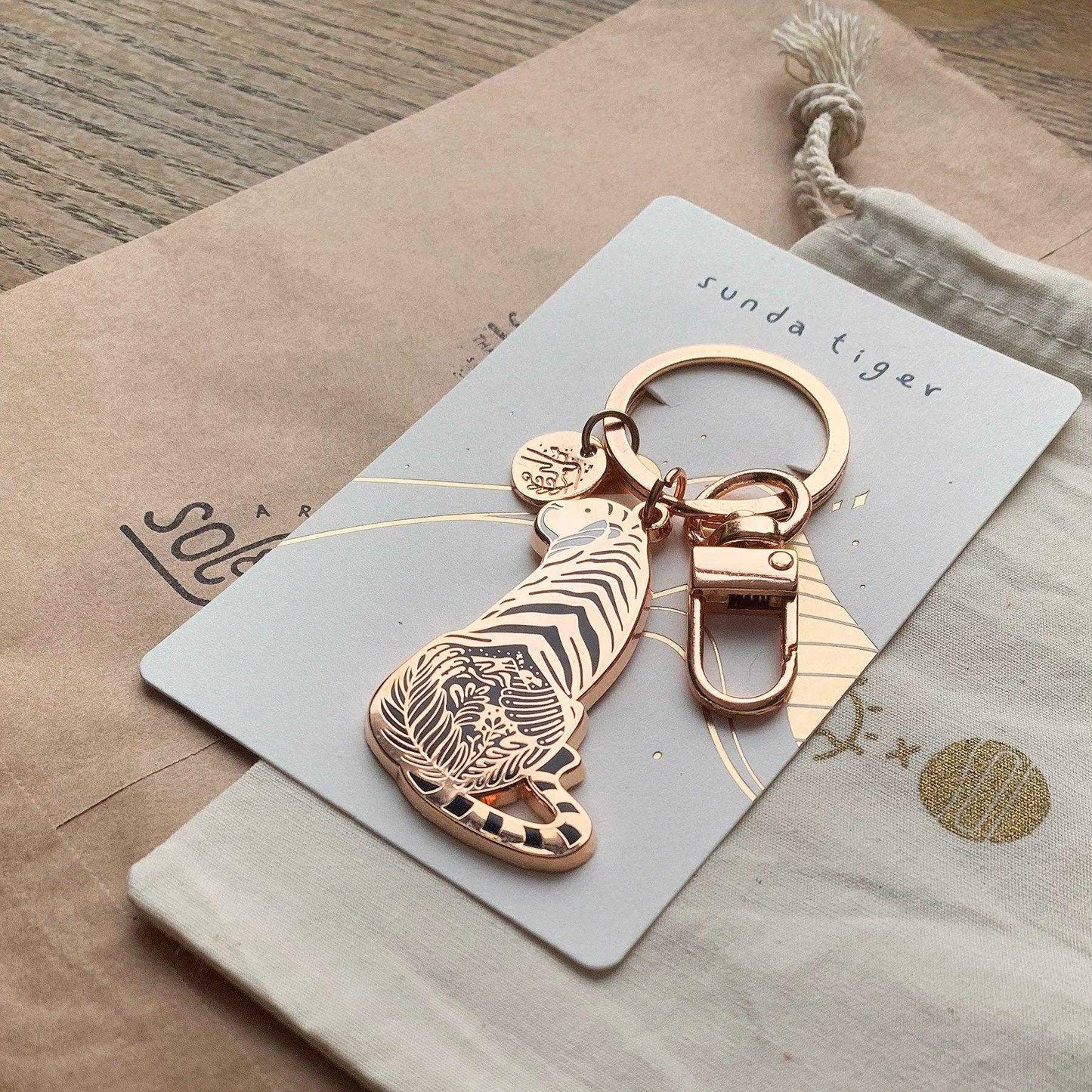Sunda Tiger enamel keychain on display card, featuring delicate habitat art and endangered species information.