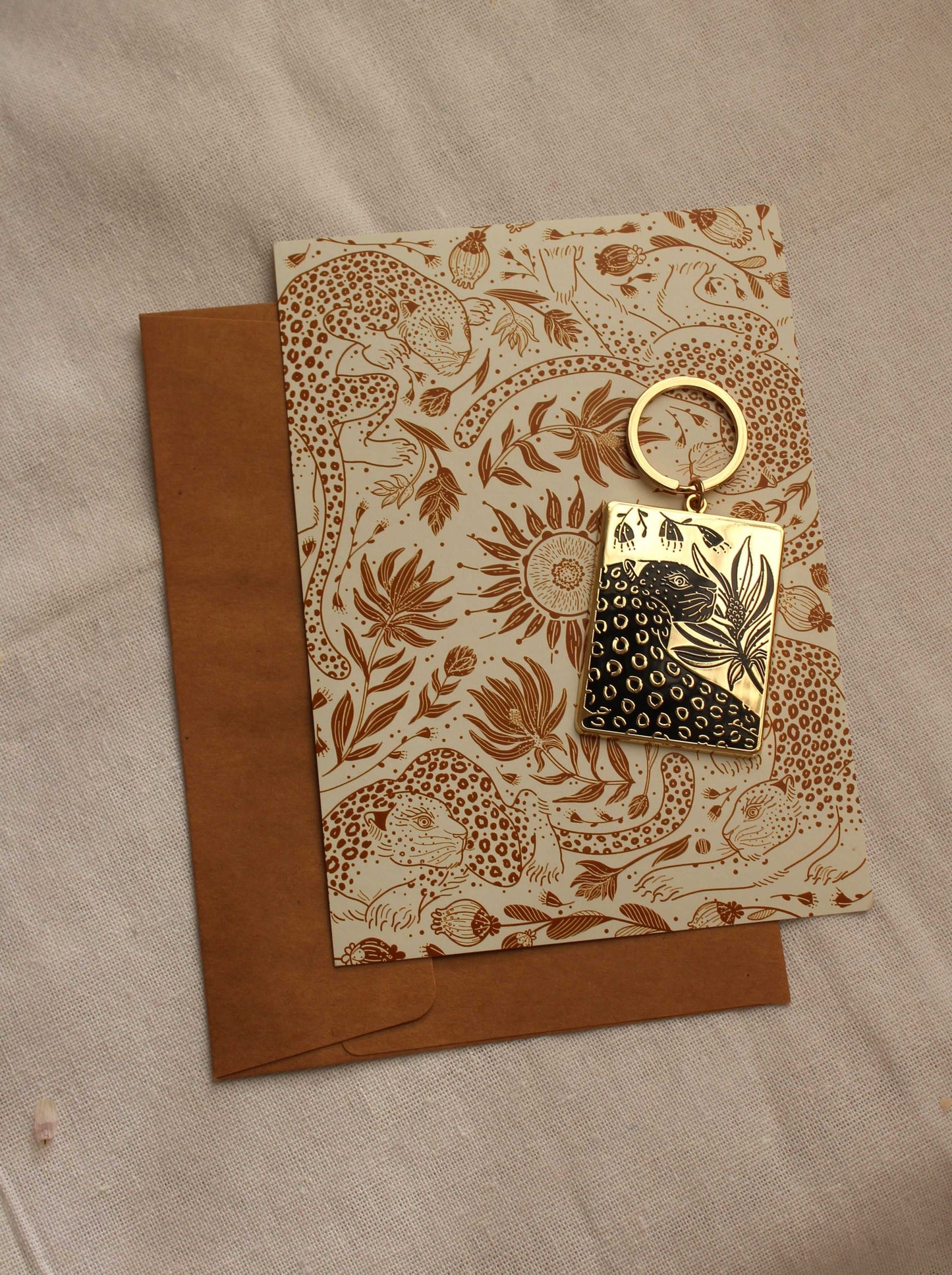 Leopard and flowers enamel keychain on patterned card, ideal for adding charm to bags and purses.