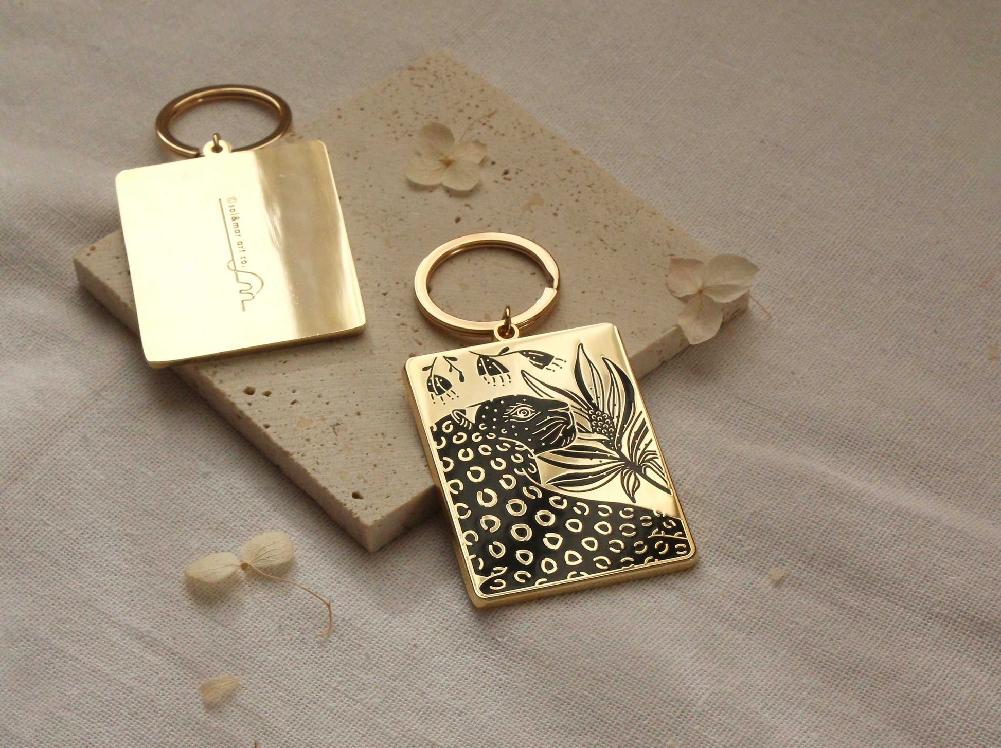 Leopard and flowers enamel keychain on textured surface with gold-plated accents. Perfect accessory for bags and purses.
