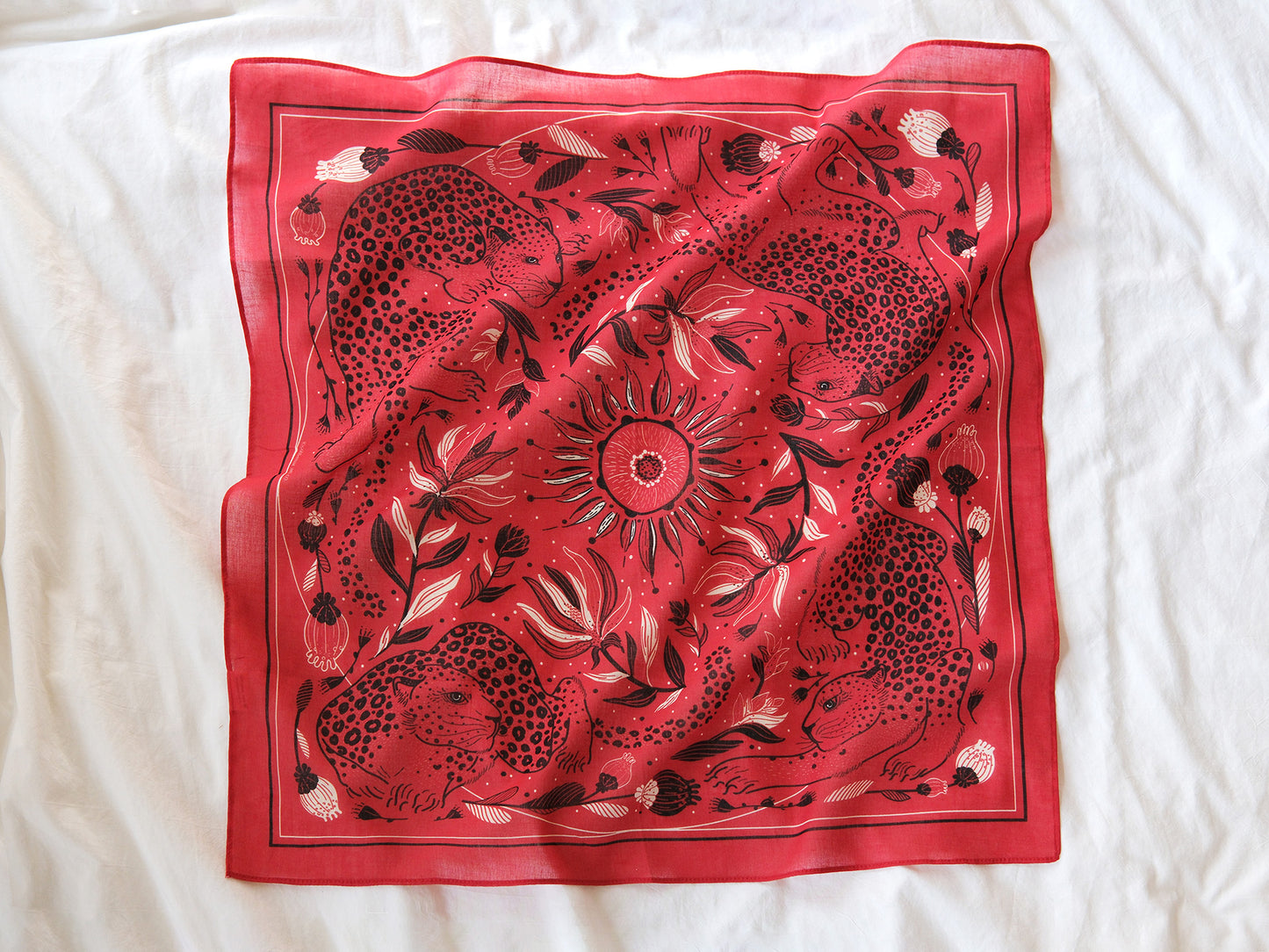 Red scarf with black floral and animal pattern on a white background
