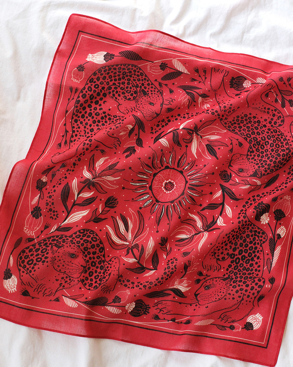 Red scarf with black floral and animal pattern on a white fabric background