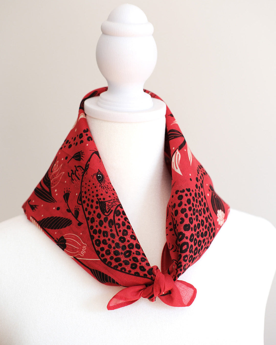 Red scarf with black animal print draped over a mannequin on a white background