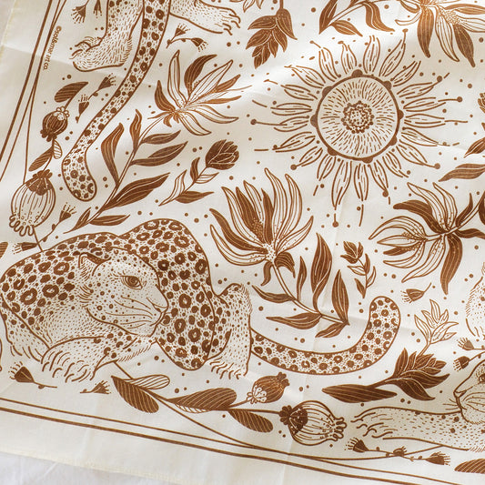Illustrated off-white bandana scarf featuring leopard and sun designs, perfect for accessories and pets.