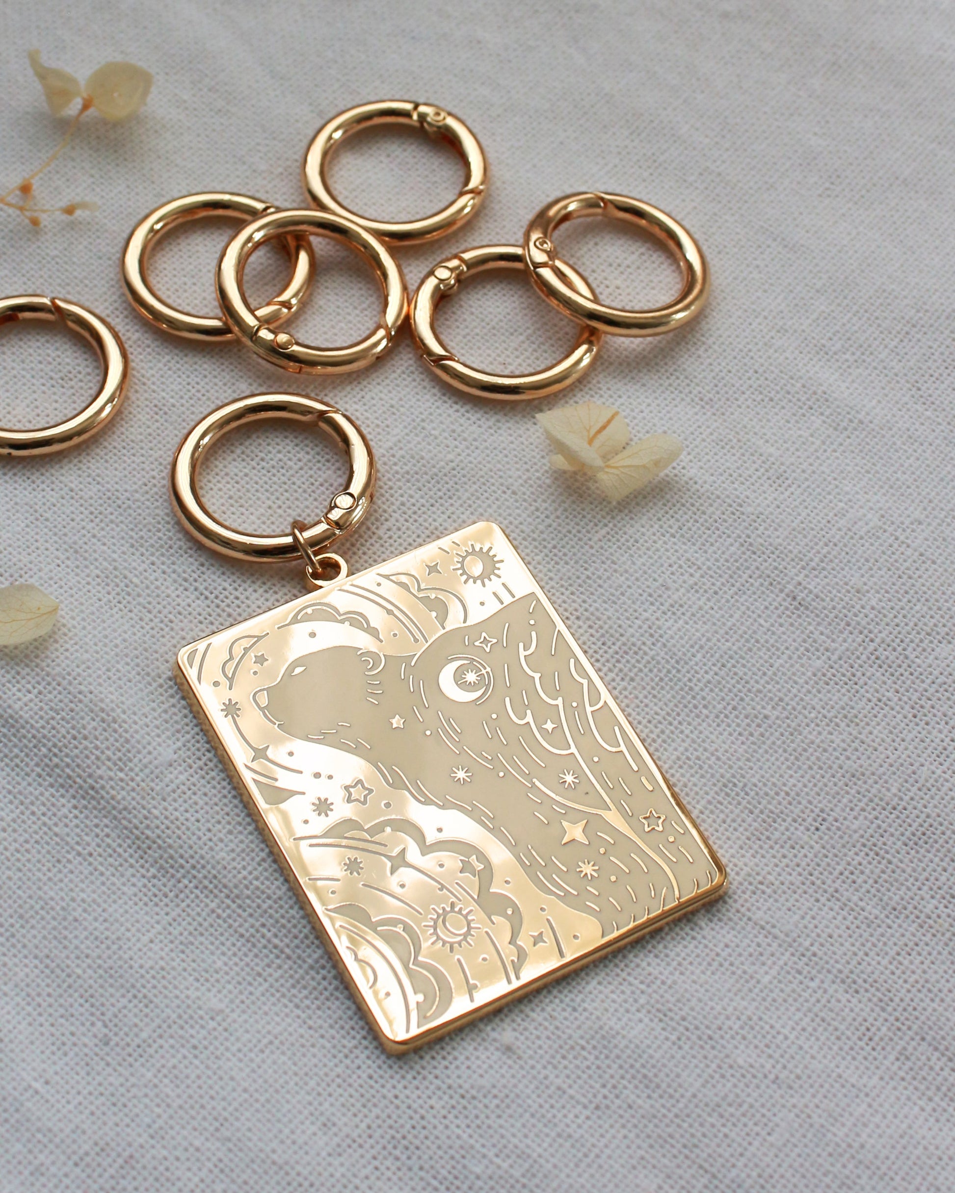 Gold-plated enamel keychain featuring a polar bear design with northern sky patterns, surrounded by metal rings.