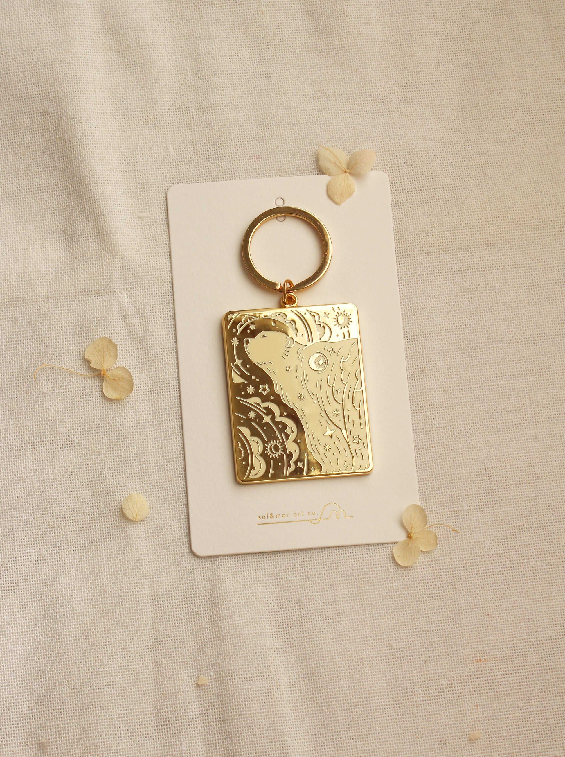 Gold-plated polar bear enamel keychain on display card against a neutral background.