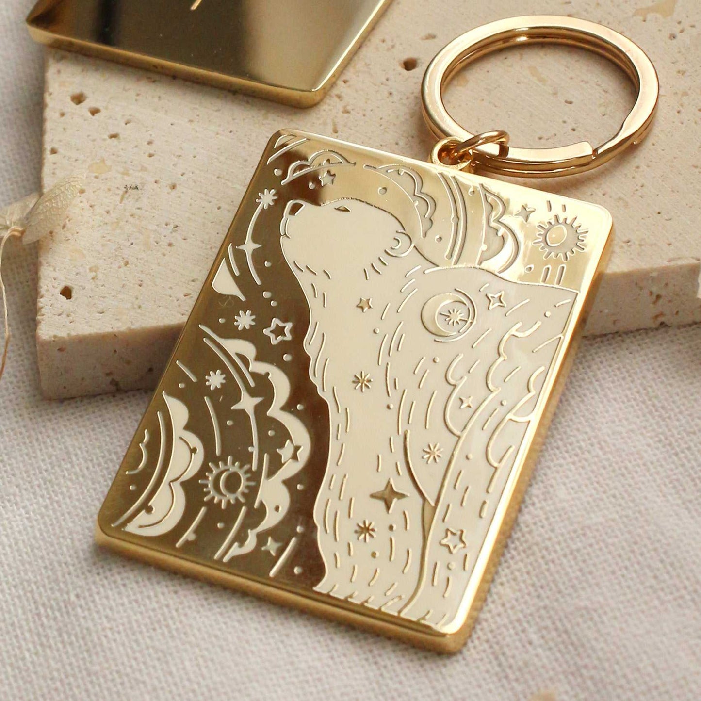 Gold-plated enamel keychain featuring a polar bear design against a starry northern sky background.