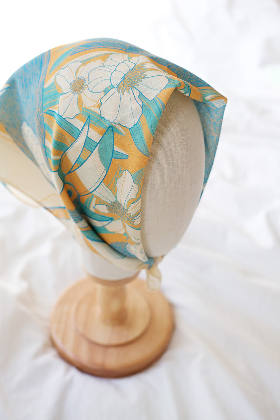 Toucan in the Floral Jungle Bandana Scarf displayed on a mannequin head, featuring vibrant yellow and blue floral patterns.