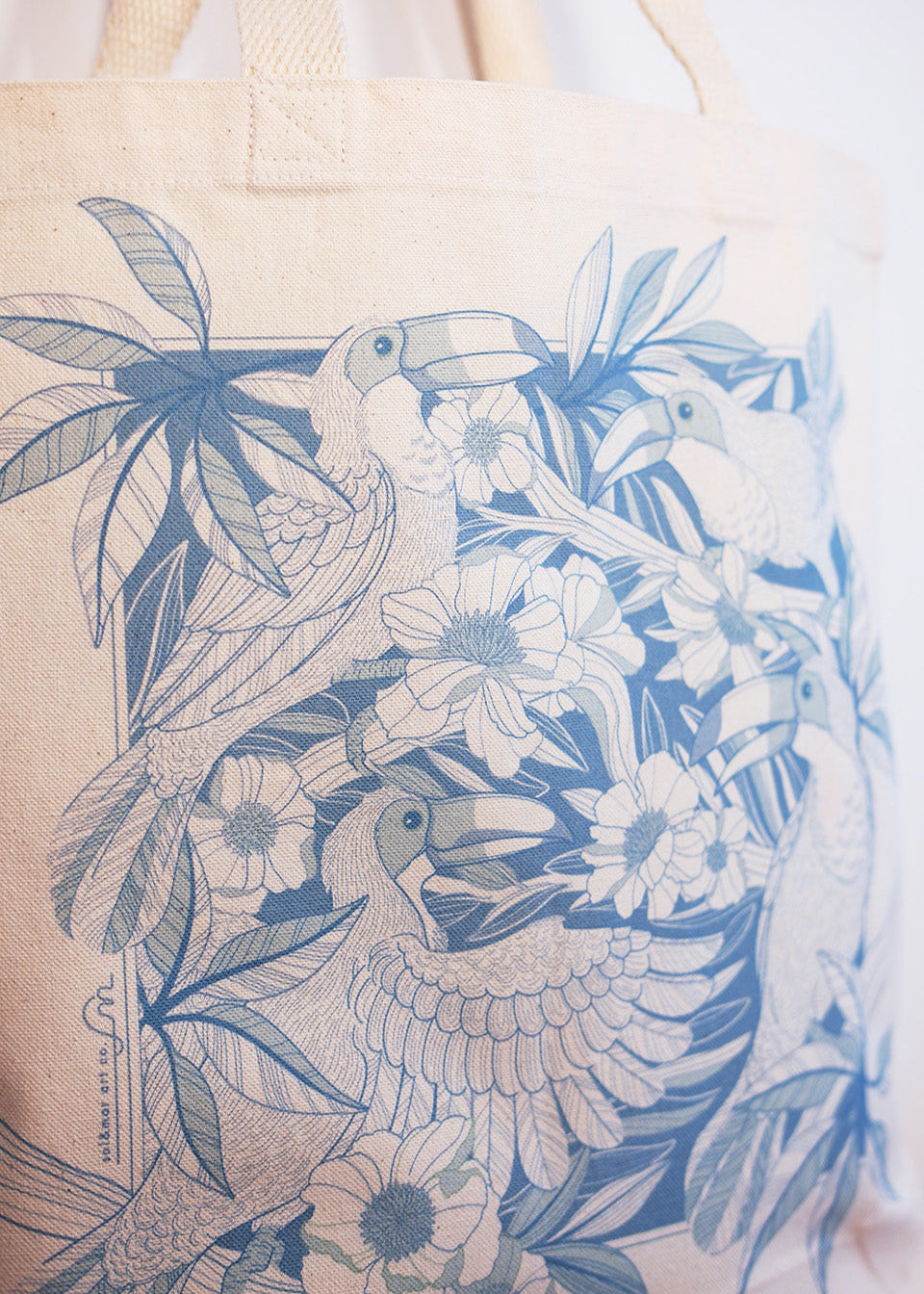 Tote bag with blue Toucan bird and floral design on a beige background