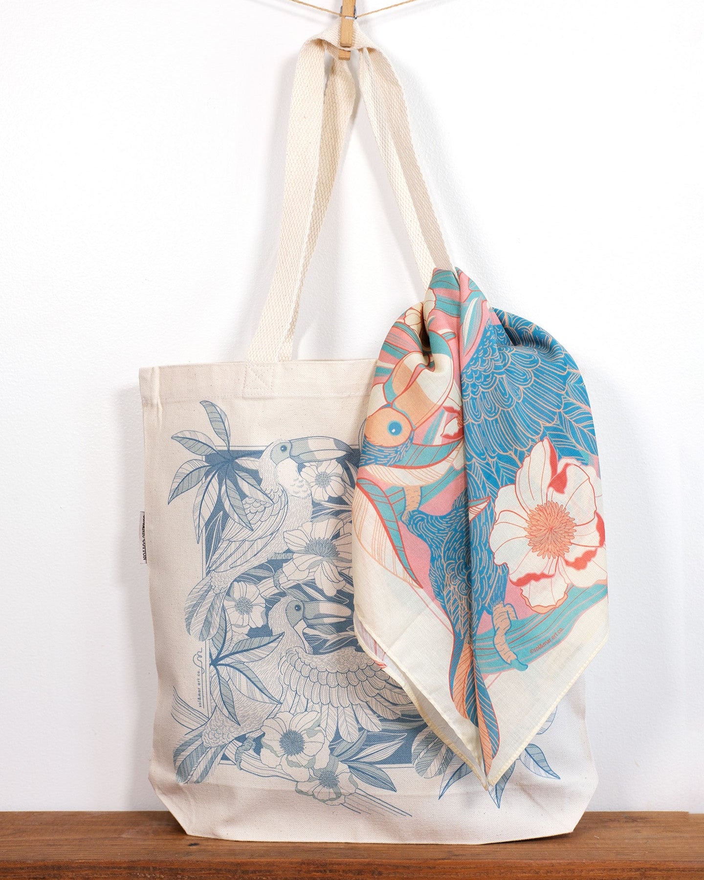 Tote bag and Toucan & floral scarf on a wooden surface with a white background