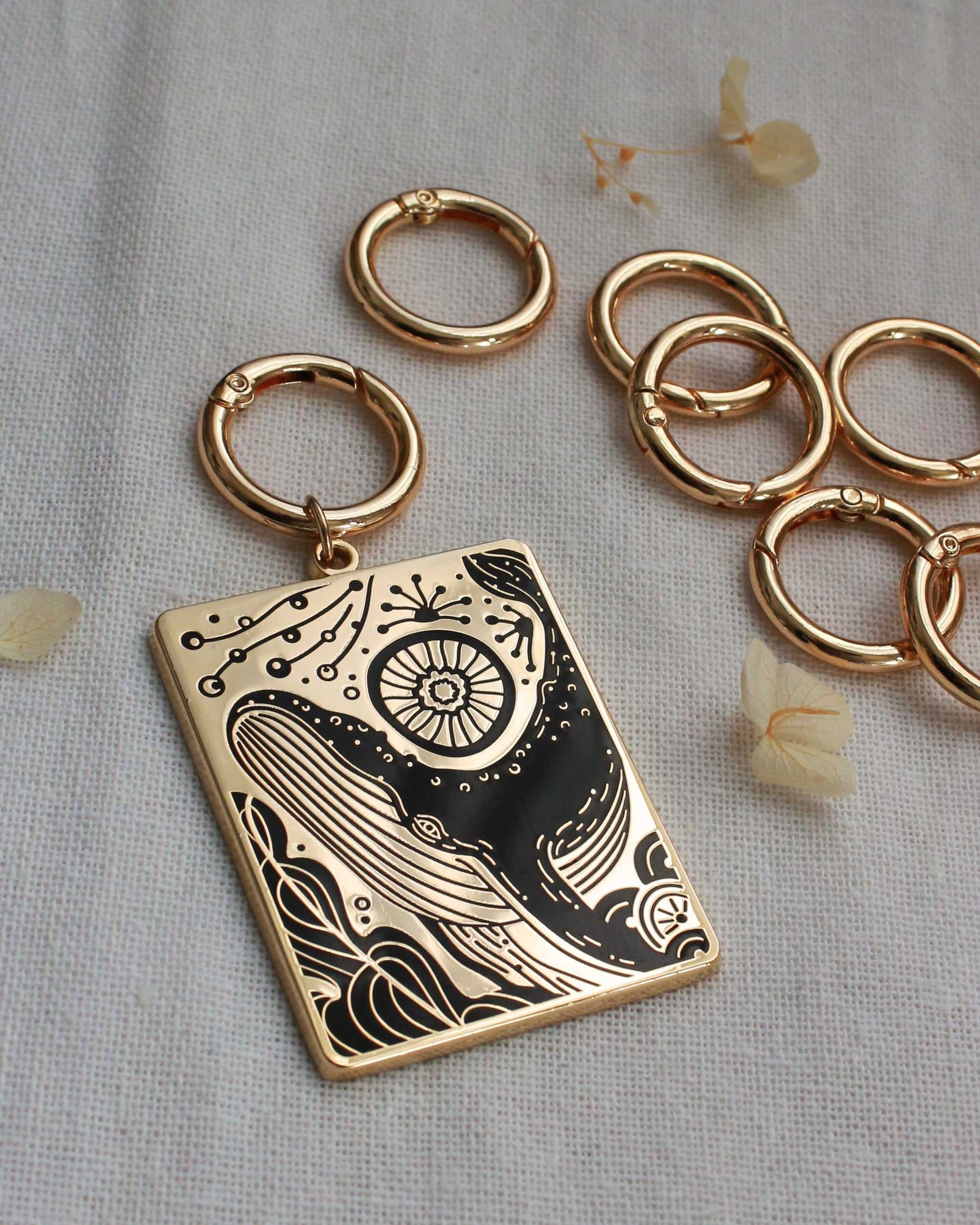 Humpback whale and ocean enamel keychain with gold plating and intricate design, displayed with metal rings.