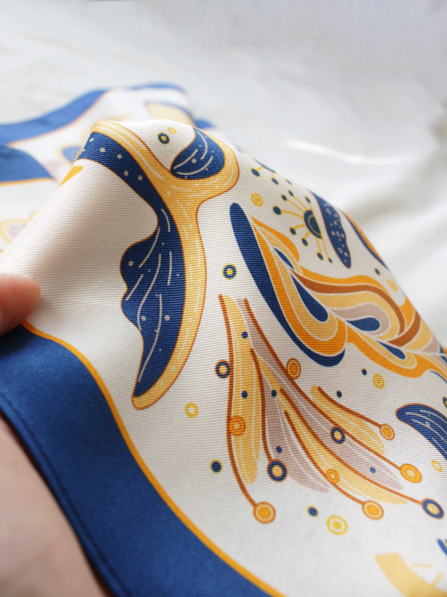 Close-up of a colorful silk twill scarf featuring abstract wave patterns and vibrant colors.