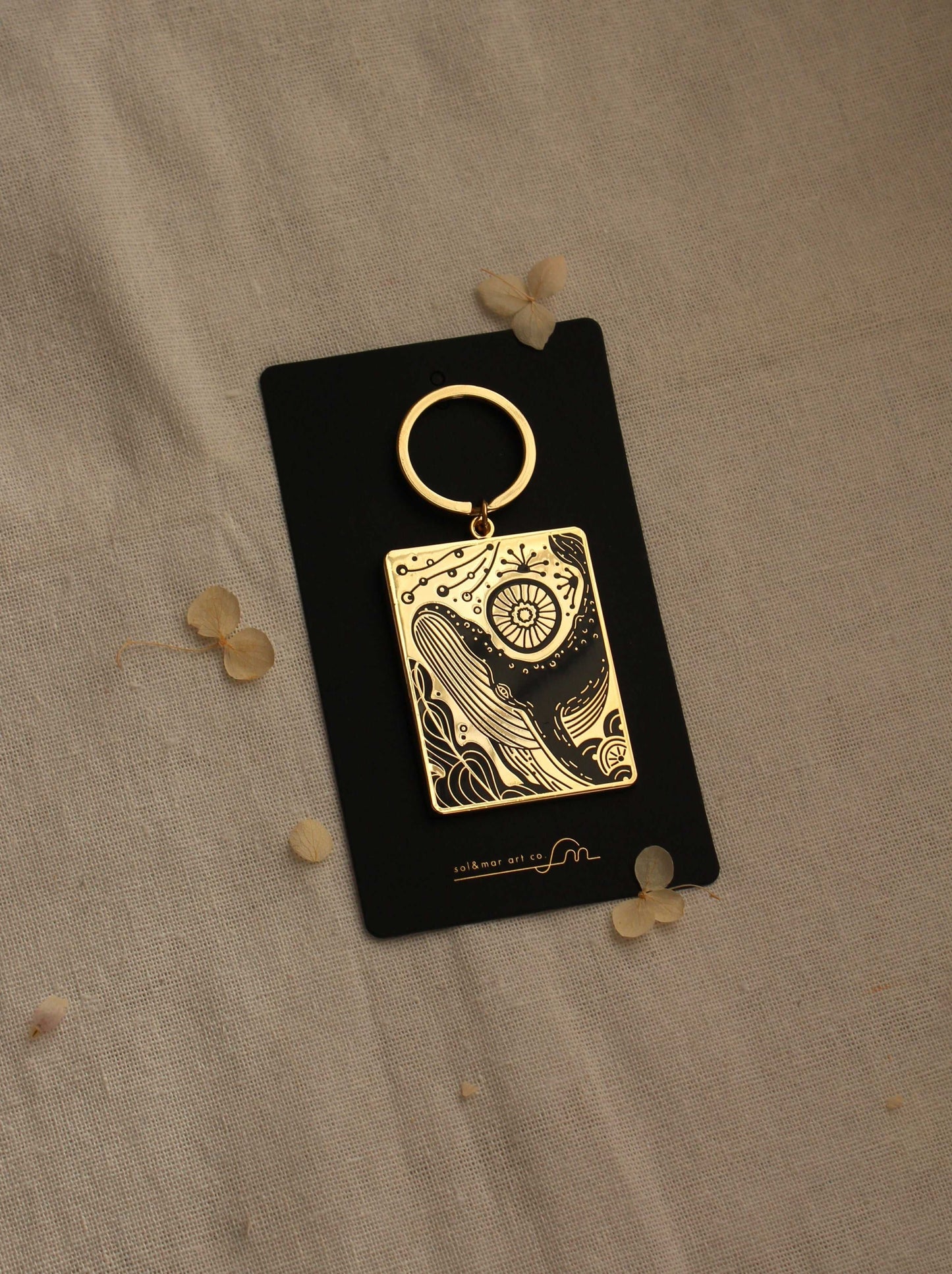 Humpback whale and ocean enamel keychain on display card with gold plating.