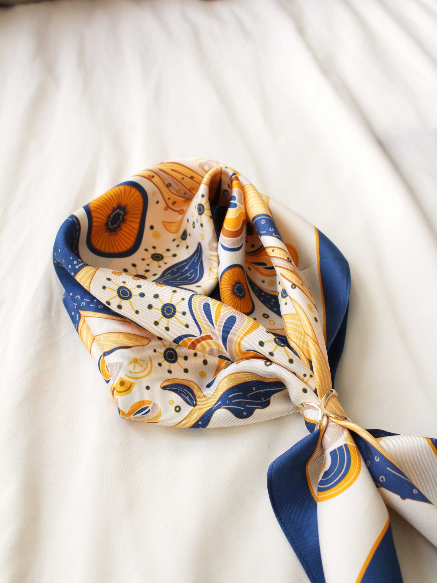 Stylish scarf featuring a colorful abstract design with orange, blue, and white patterns, elegantly draped.