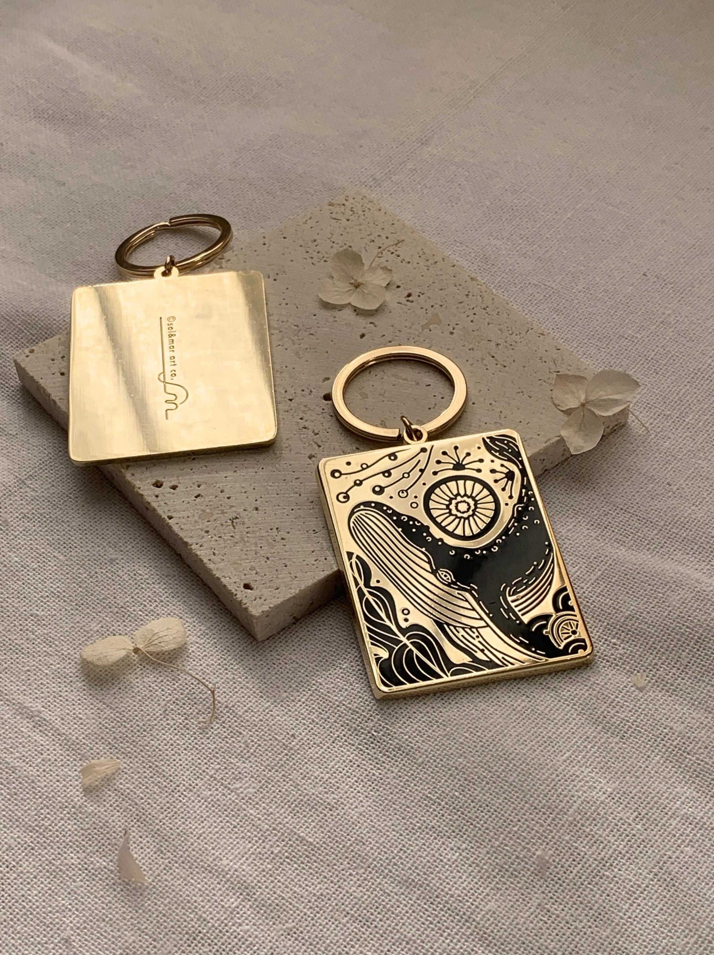 Humpback whale and ocean enamel keychain on a textured surface, showcasing intricate design details.