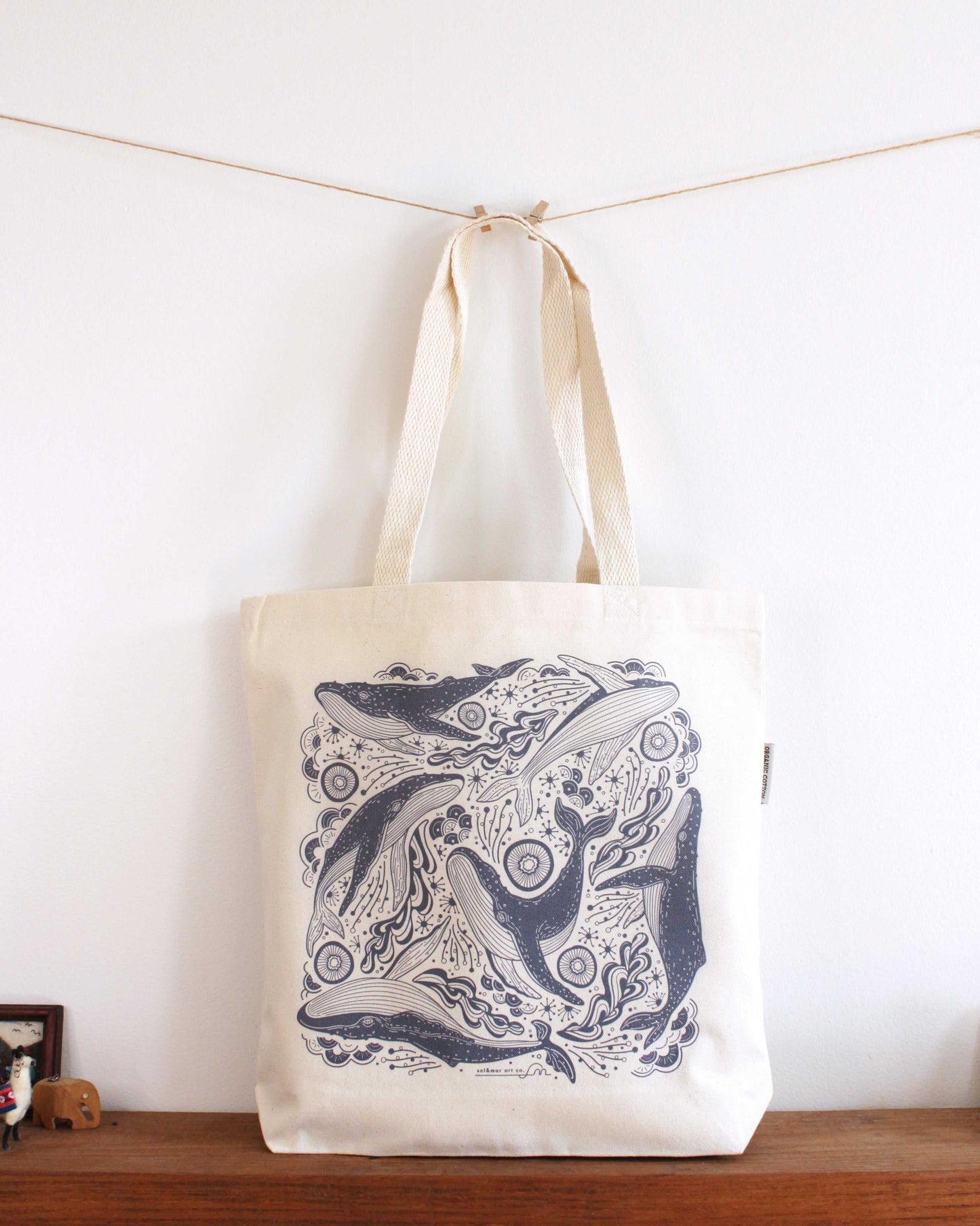 Whale and ocean illustrated canvas tote bag on display with sturdy handles, perfect for everyday use.