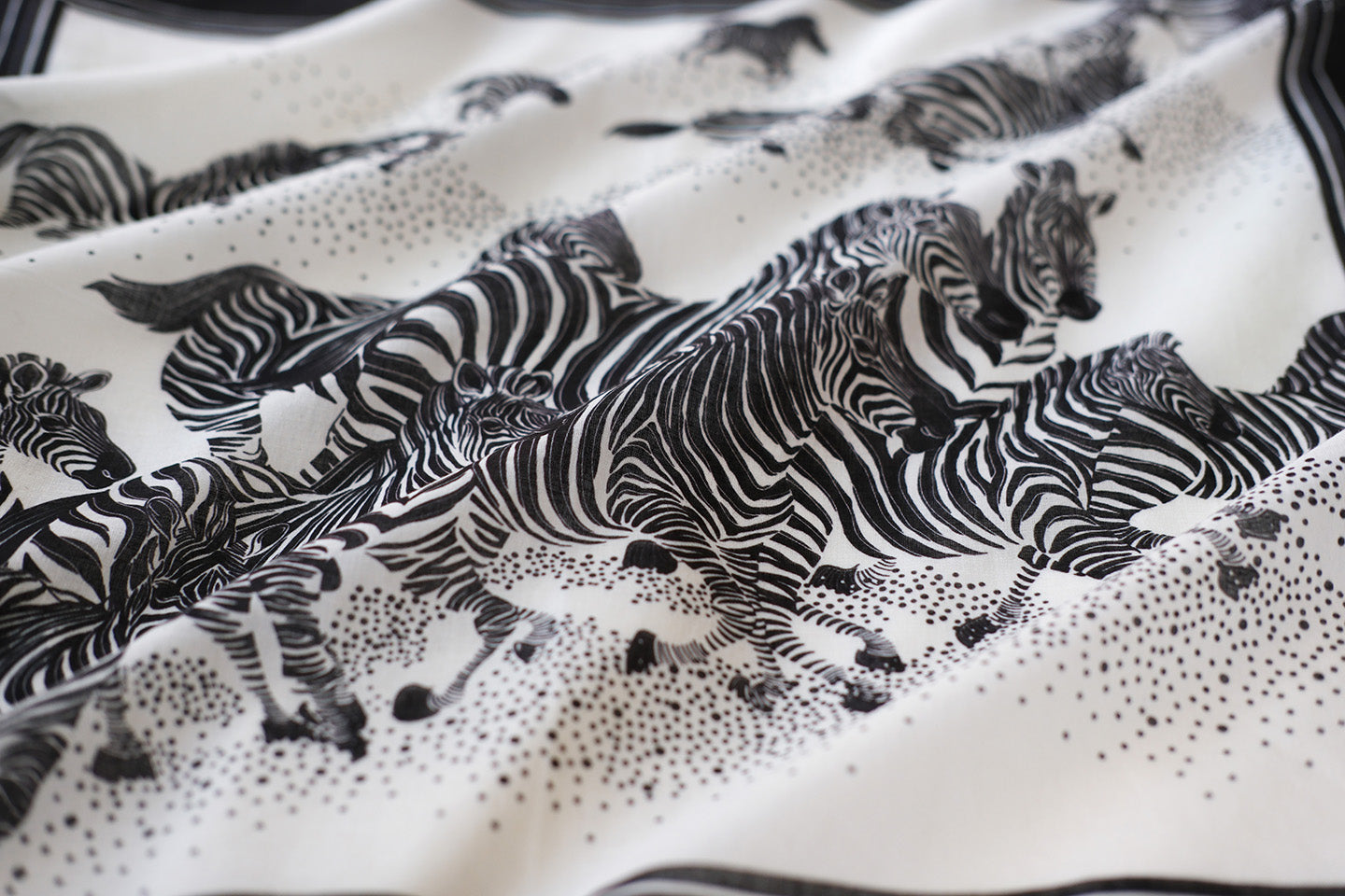 Black and white bandana scarf featuring a herd of zebras running across a soft cotton fabric.