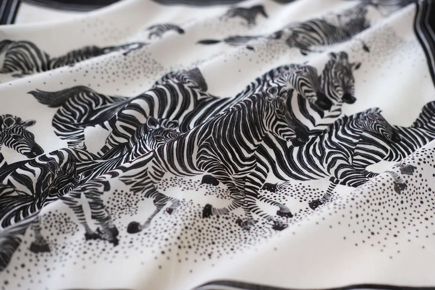 Black and white bandana scarf featuring a herd of zebras running across a soft cotton fabric.