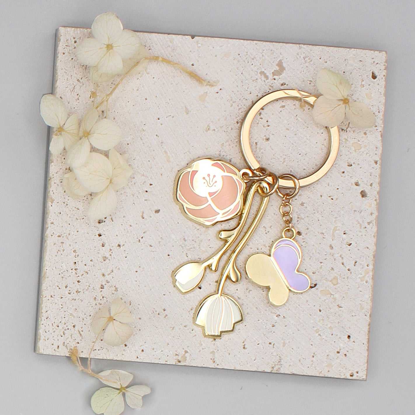 Minimal Garden Keychain featuring gold-plated rose, peony, and butterfly charms on a textured display card.