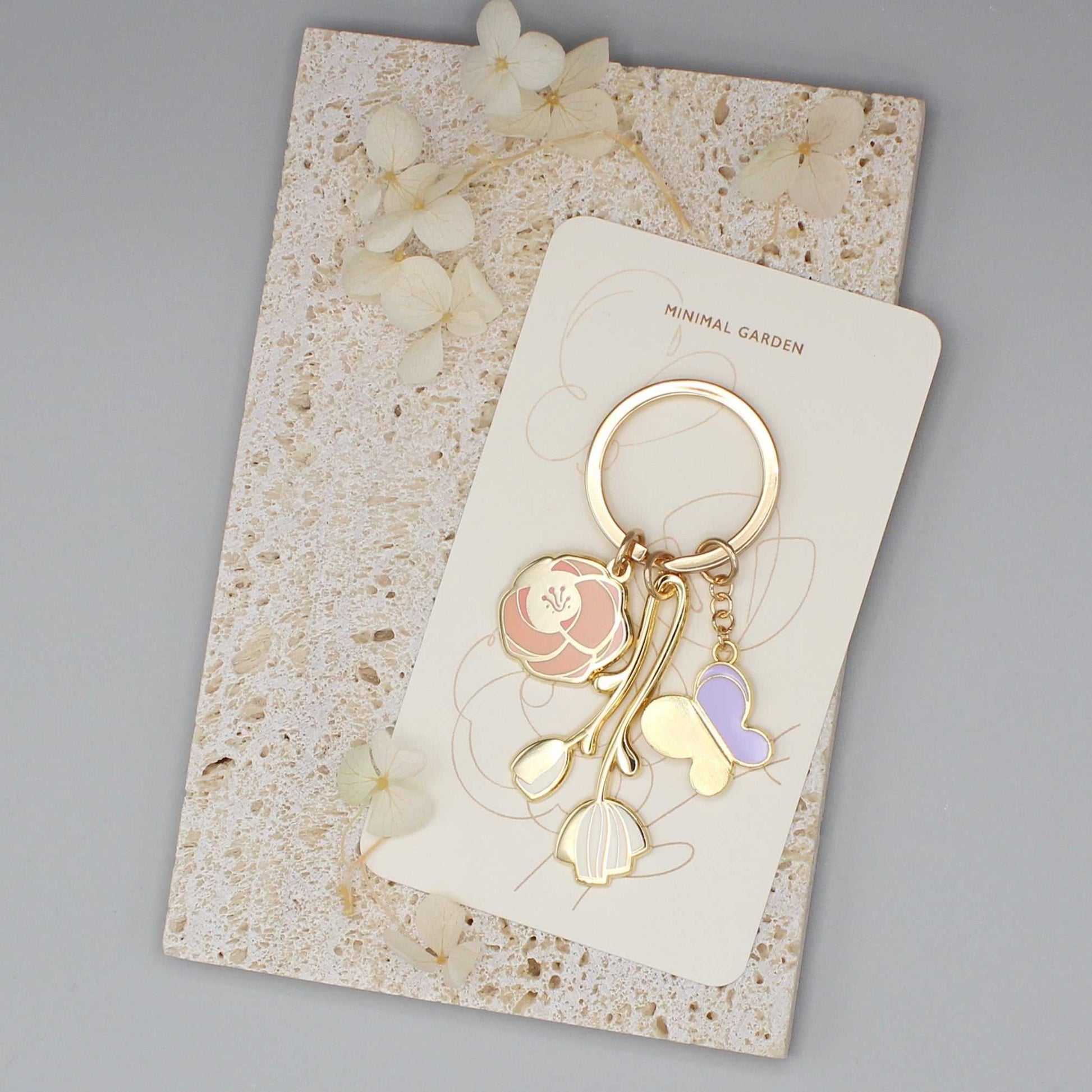 Minimal Garden Keychain featuring gold-plated flower and butterfly charms on a display card.