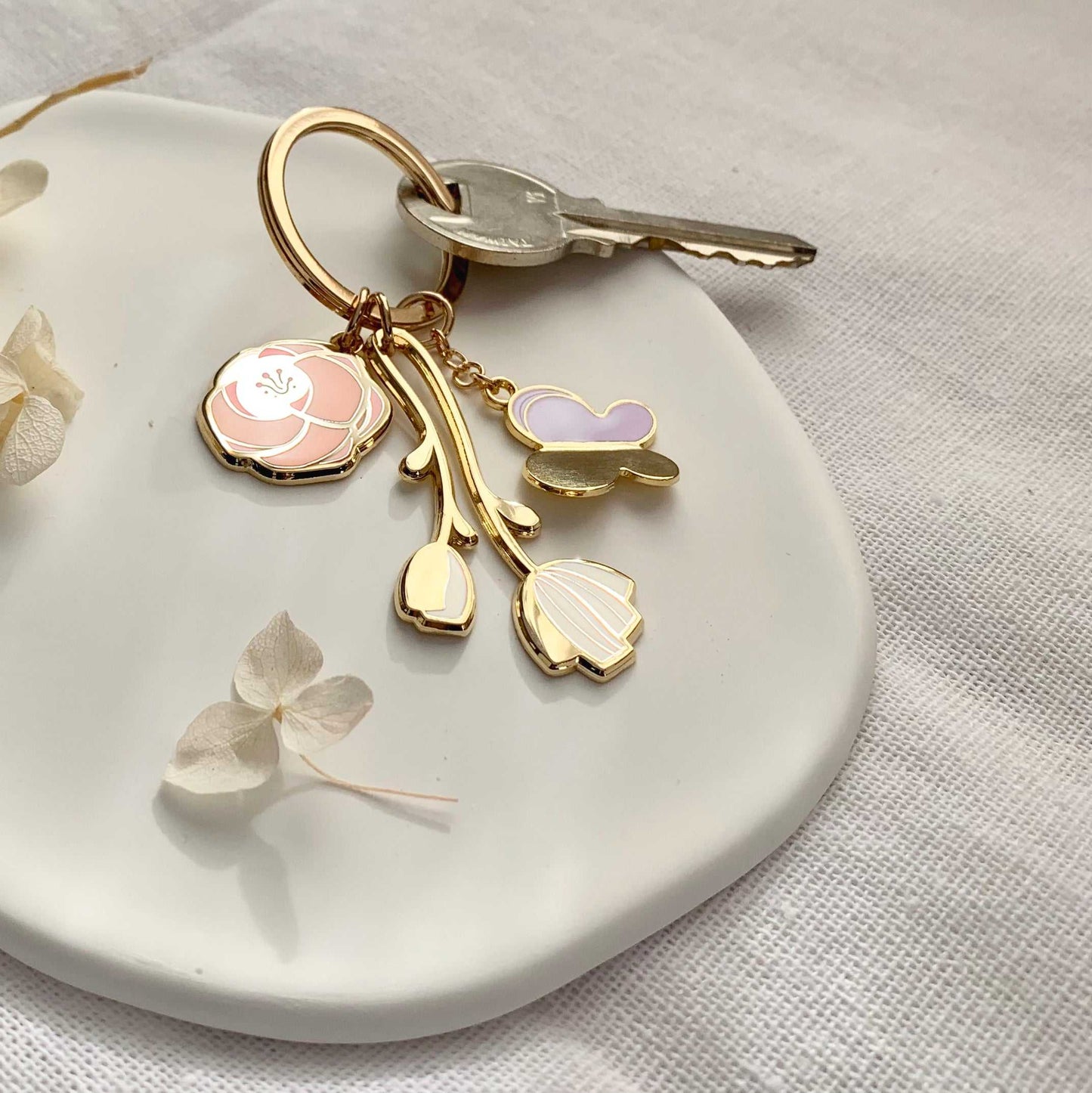 Minimal Garden Keychain with flower and butterfly charms on a white plate, featuring gold plating and simple design.