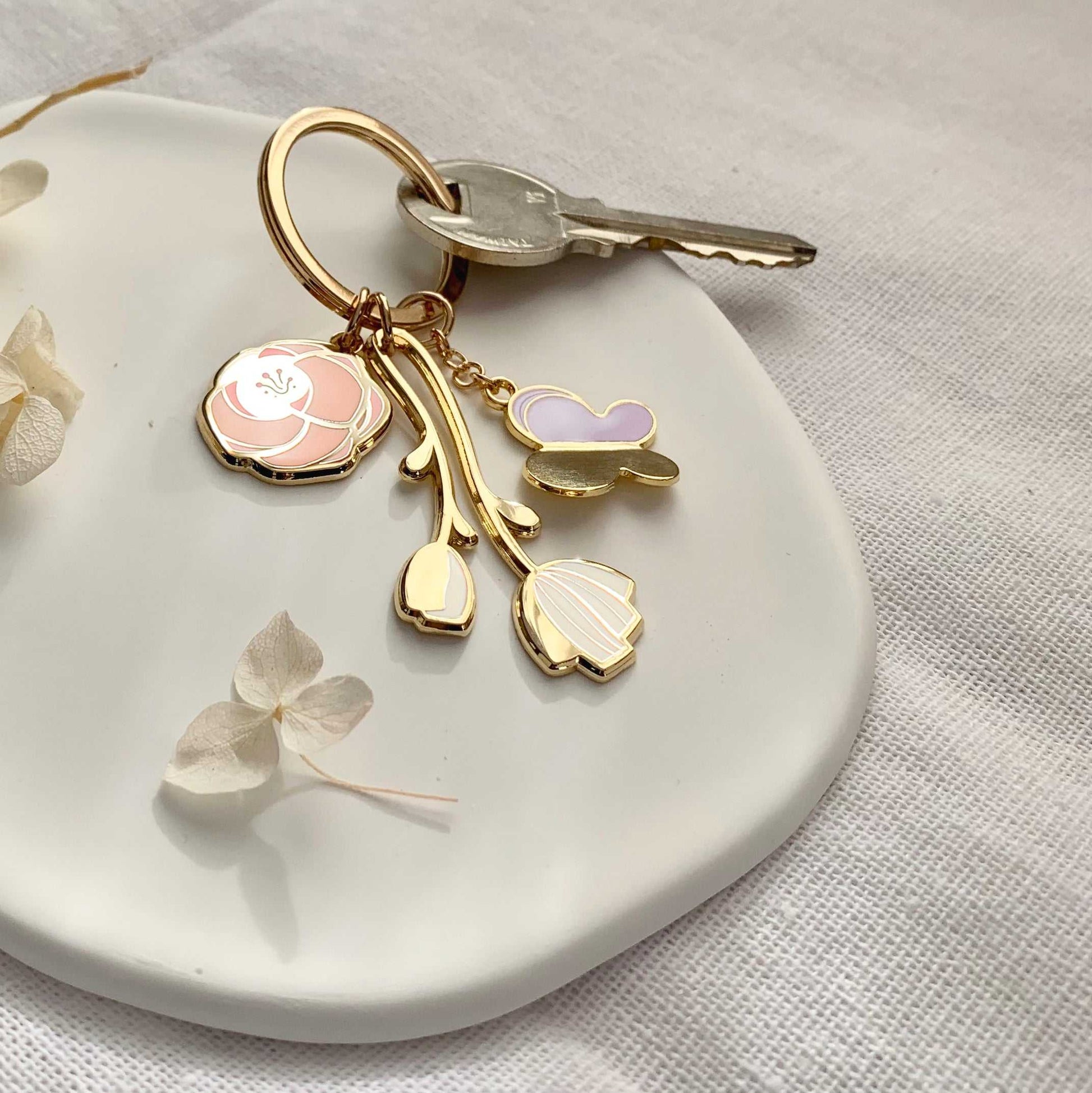 Minimal Garden Keychain with flower and butterfly charms on a white plate, featuring gold plating and simple design.