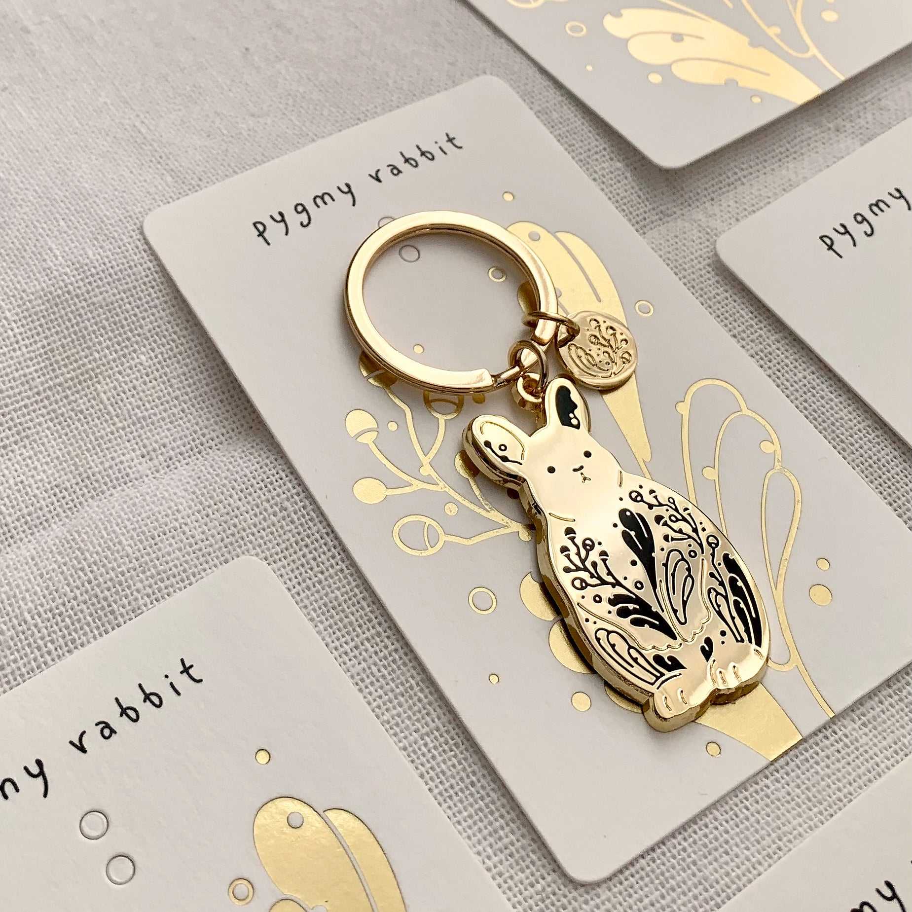Gold pygmy rabbit keychain on an illustrated display card, highlighting its endangered status and sagebrush habitat.