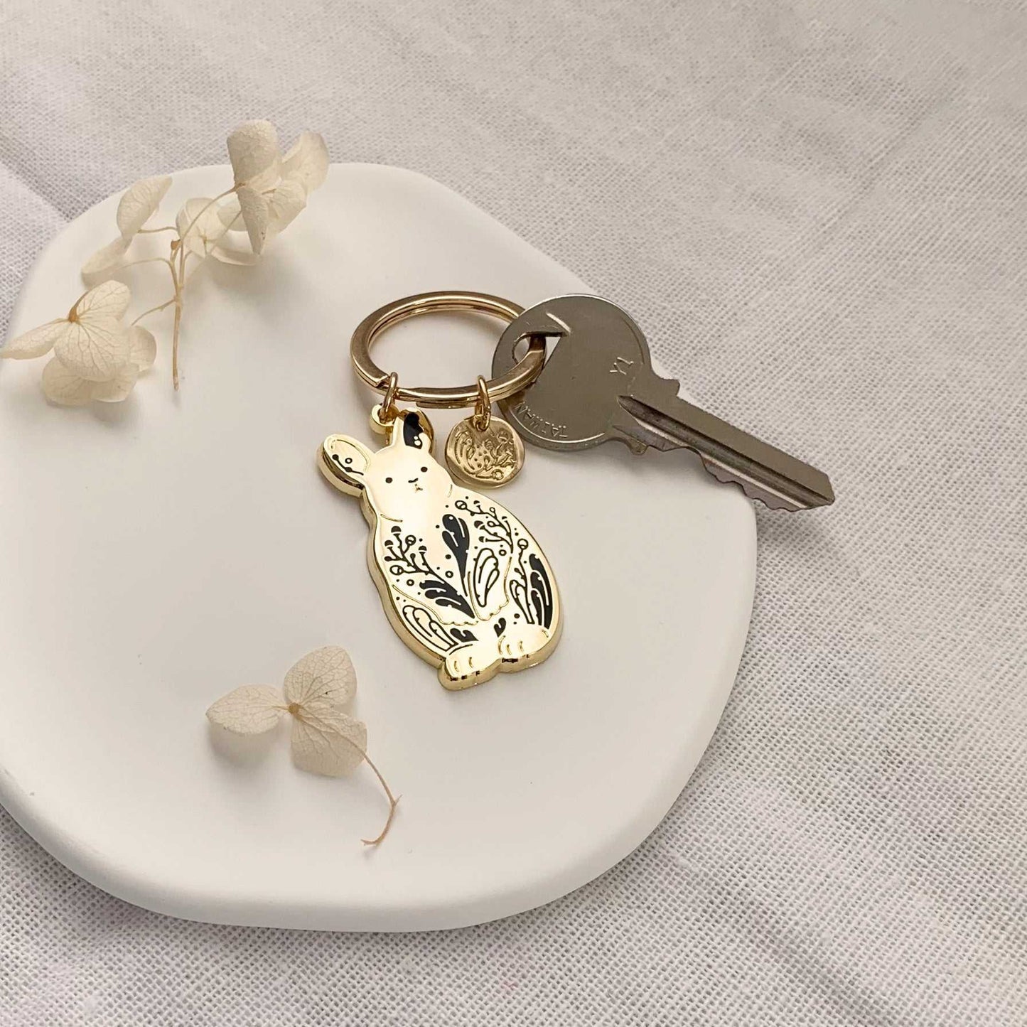 Bunny rabbit keychain with sagebrush design on a white dish with a key and dried flowers.
