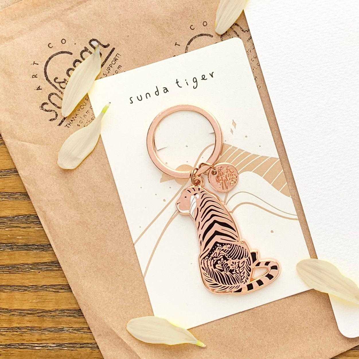 Sunda Tiger enamel keychain featuring delicate habitat art and an organic round tag, promoting endangered species awareness.
